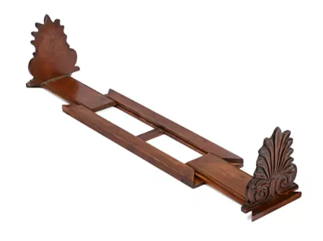 AN ANTHEMION CARVED MAHOGANY EXPANDING BOOK RACK, IN REGENCY STYLE
