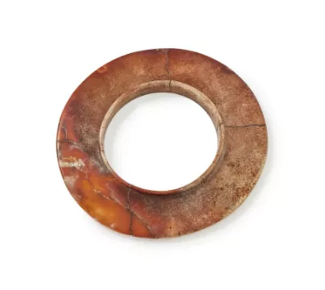 A Chinese mottled jade collared disc, yuan, Late Shang Dynasty, circa 1200 BC