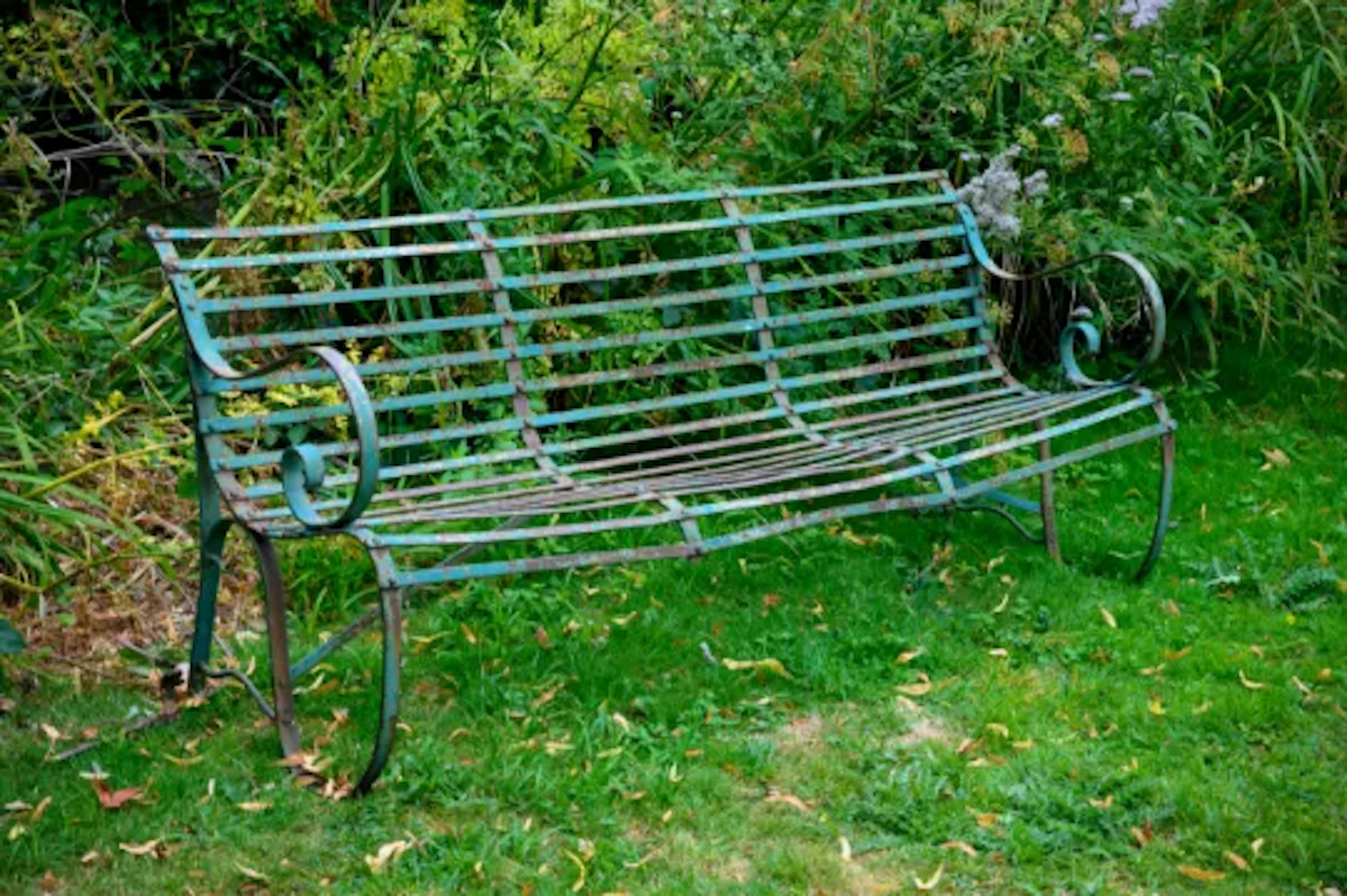 AN EDWARDIAN WROUGHT IRON STRAPWORK GARDEN BENCH, PROBABLY BY BOULTON