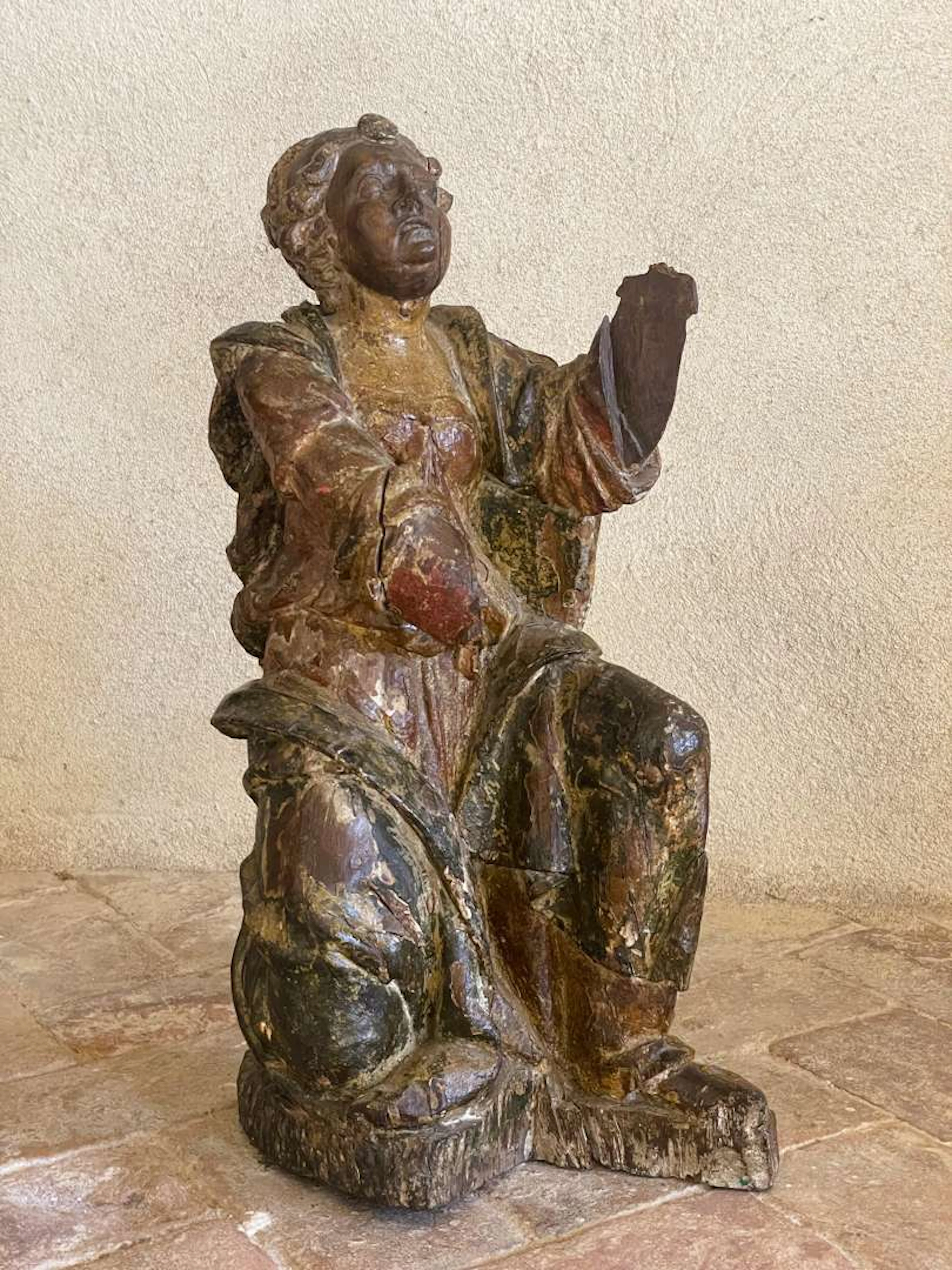 Statue of a saint on his knees, carved from wood