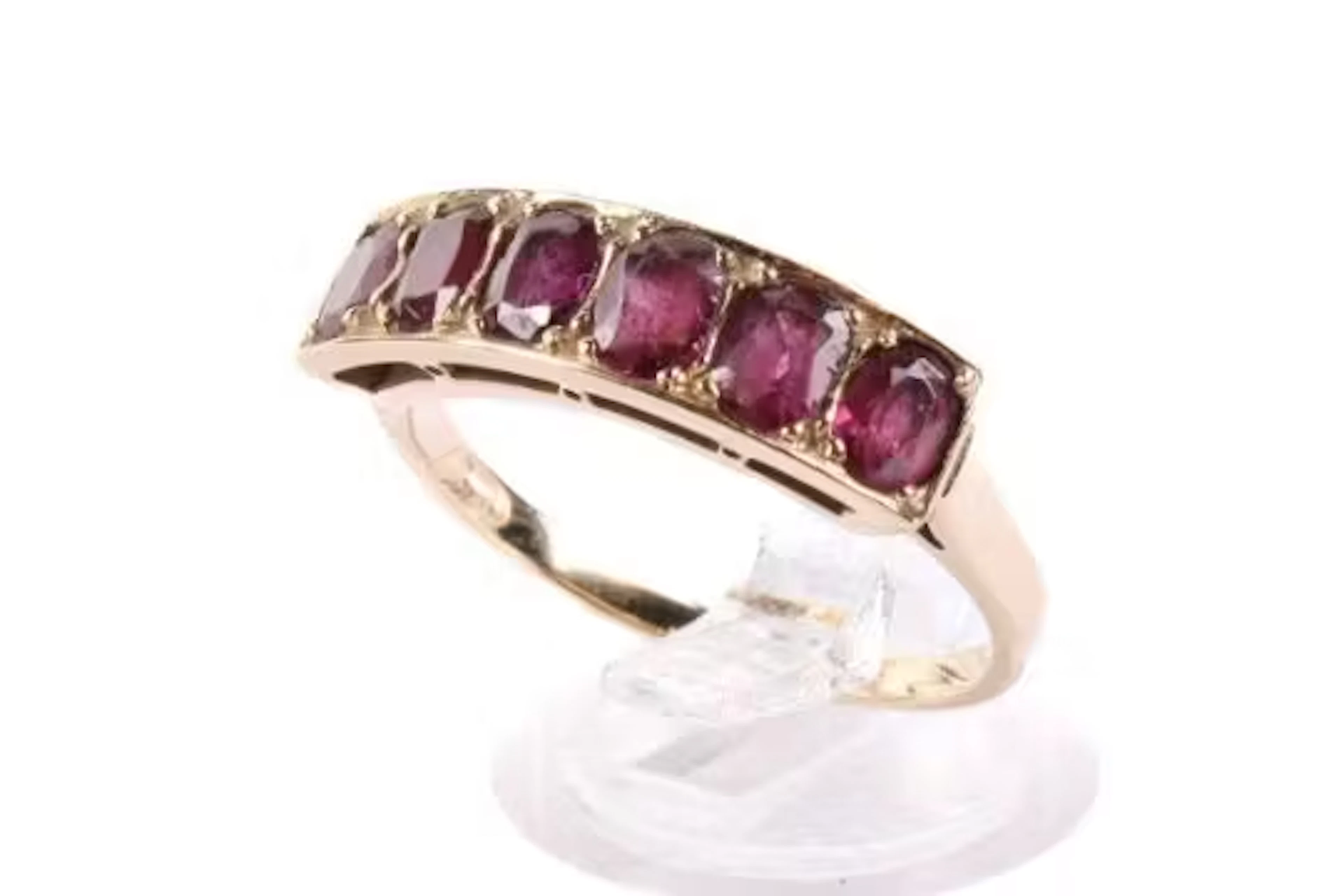 A yellow metal ring set with oval faceted garnets. Unmarked, but tested