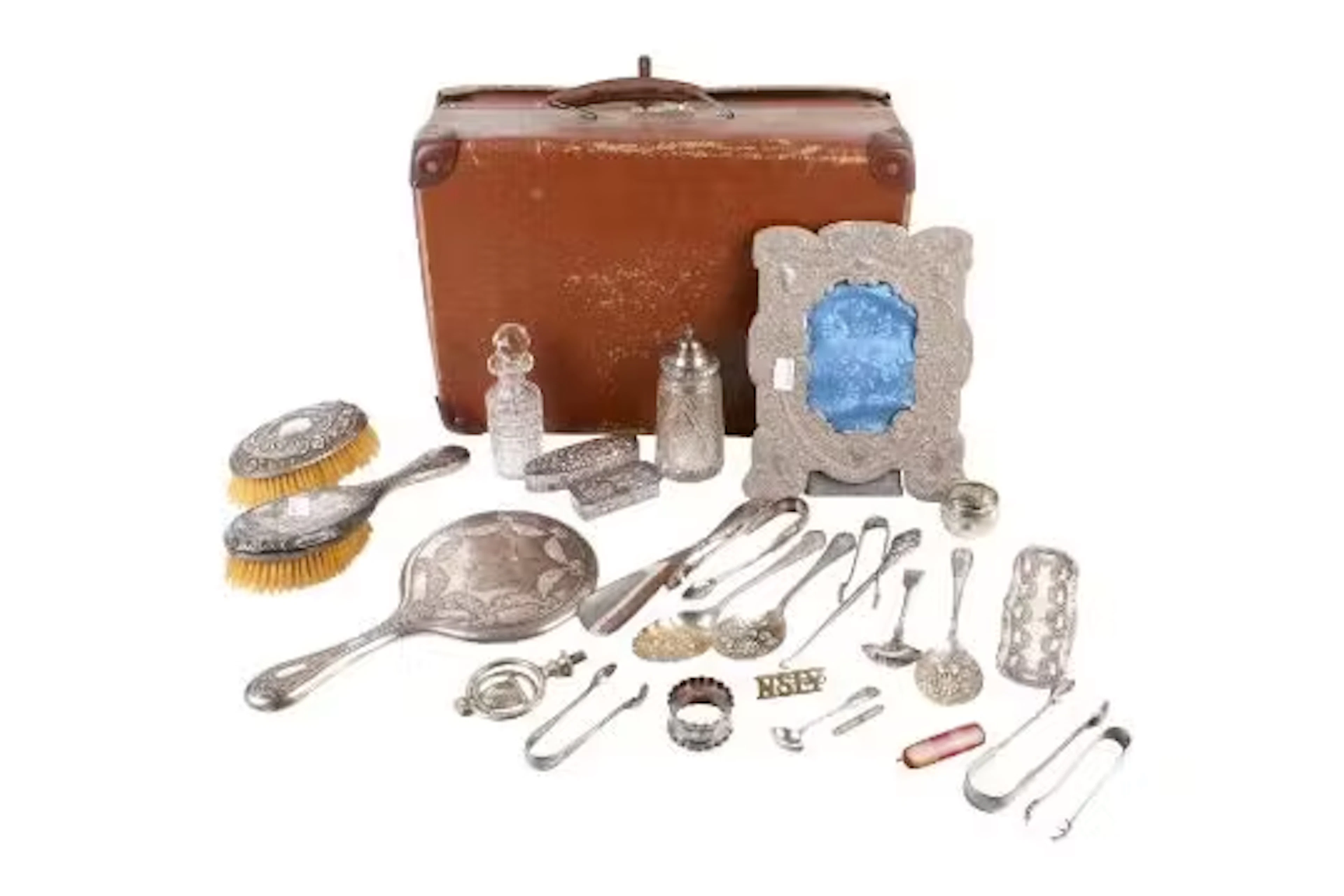 A small group of silver and white metal table items in a vintage suitcase.