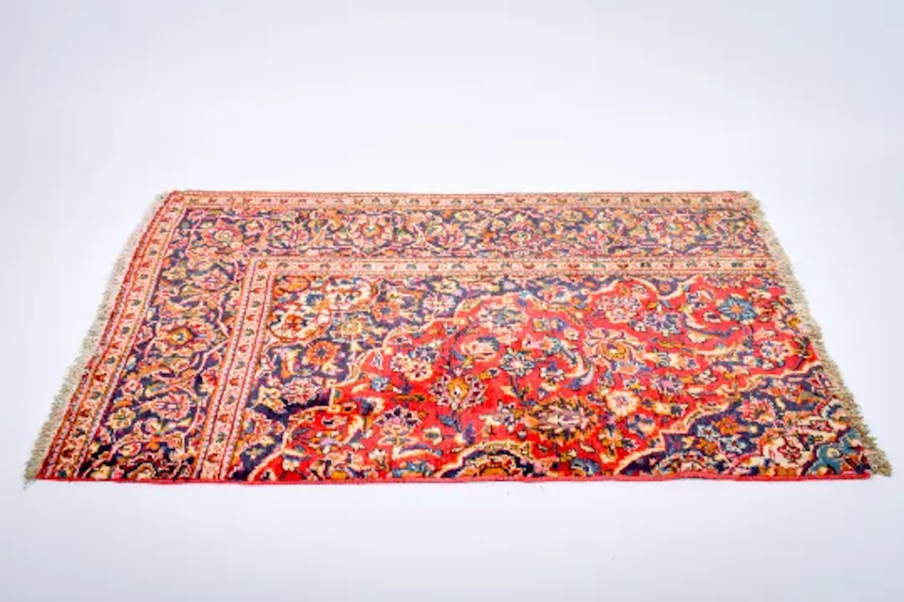 A 'cut down' Persian style woollen rug. Featuring a scrolling design