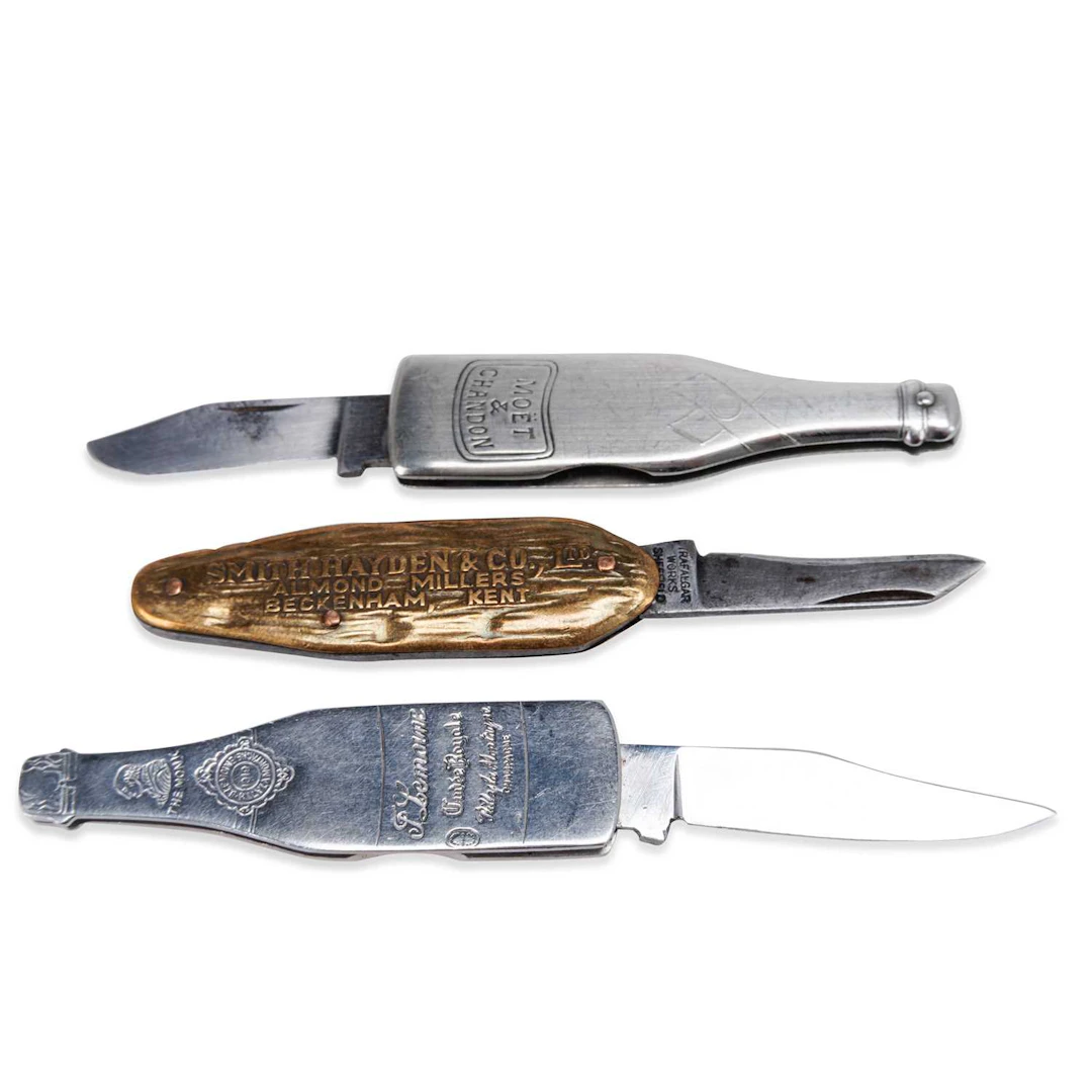 TWO NOVELTY WINE BOTTLE PEN KNIVES AND AN ADVERTISING KNIFE EARLY 20TH CENTURY