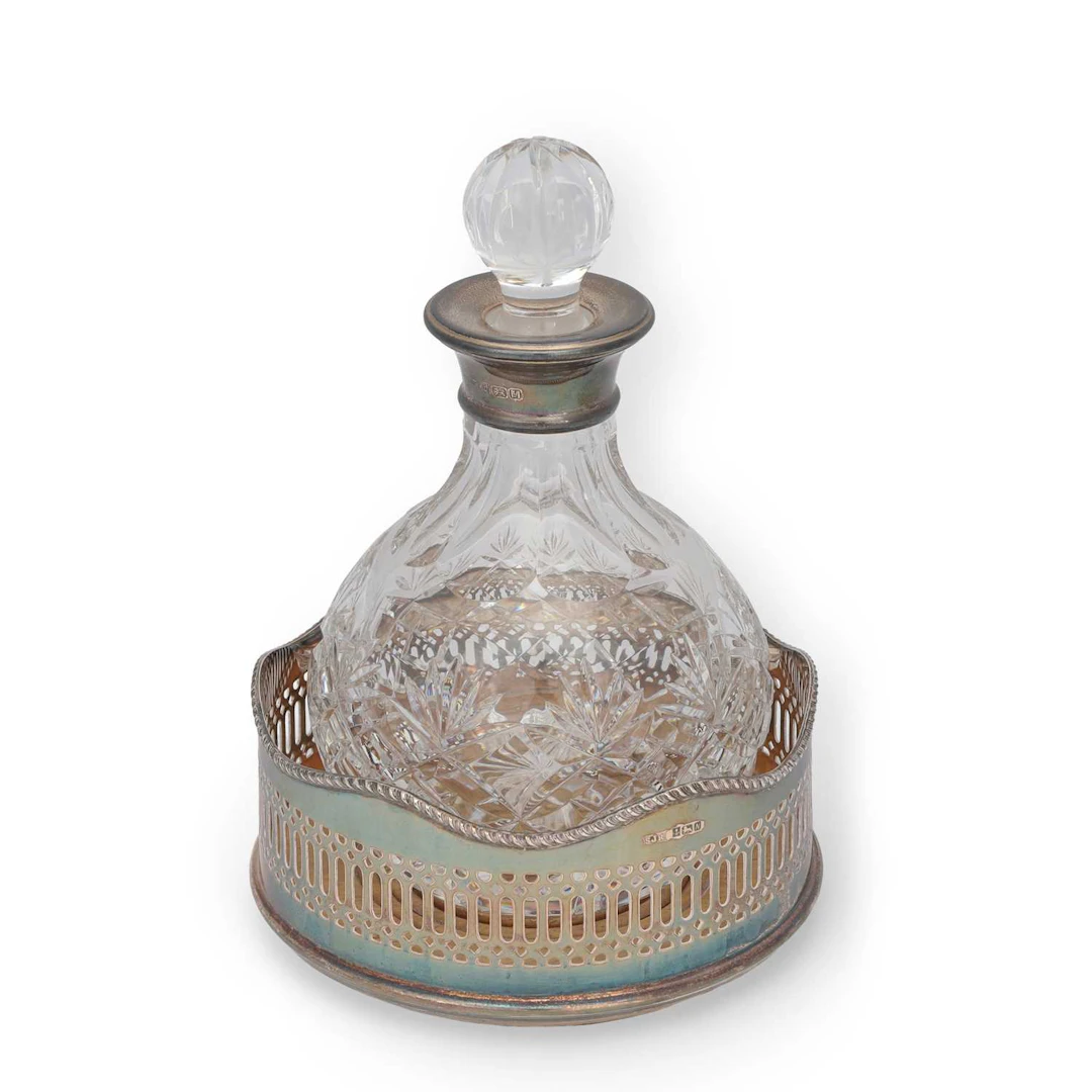 A SILVER-MOUNTED GLASS DECANTER AND A SILVER WINE COASTER