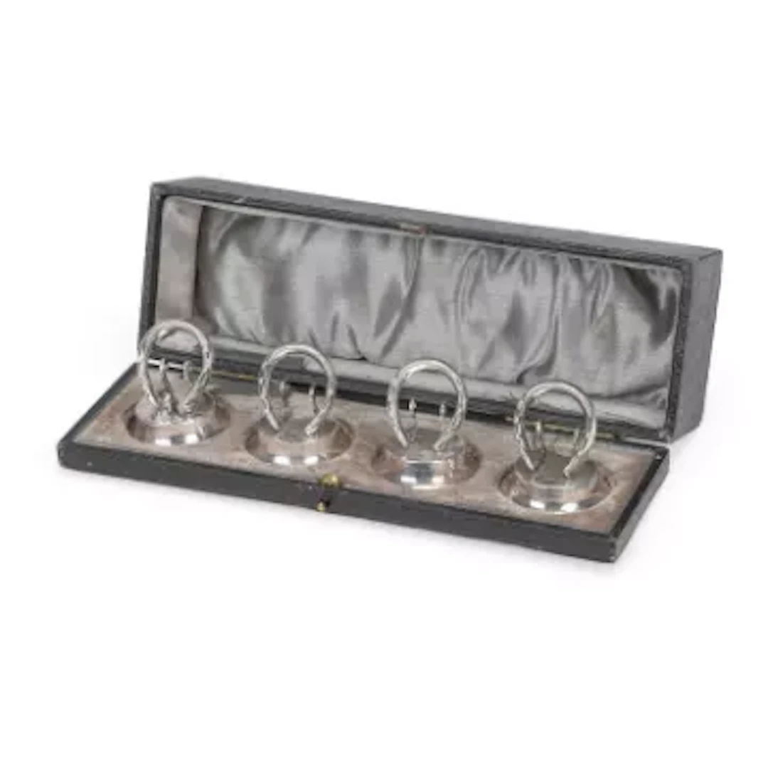 A CASED SET OF FOUR GEORGE V SILVER HORSESHOE MENU HOLDERS