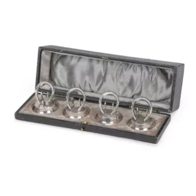 A CASED SET OF FOUR GEORGE V SILVER HORSESHOE MENU HOLDERS
