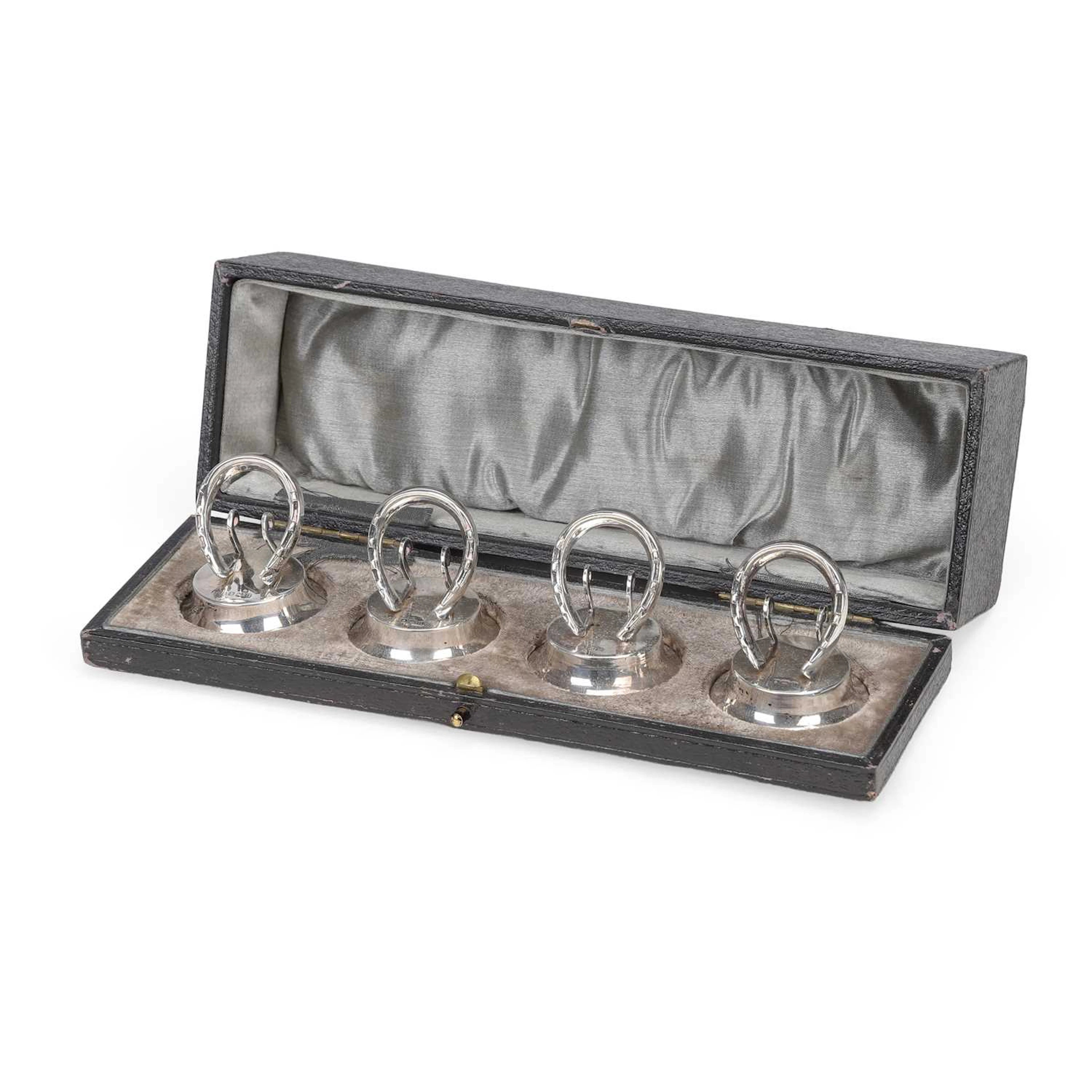 A CASED SET OF FOUR GEORGE V SILVER HORSESHOE MENU HOLDERS