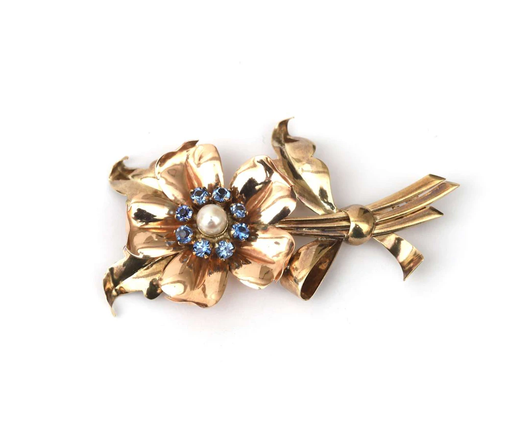 A rose gold retro flower brooch with a cultured pearl and blue glass