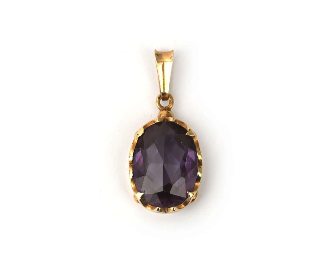 A 14k yellow gold pendant with a colour-changing synthetic sapphire