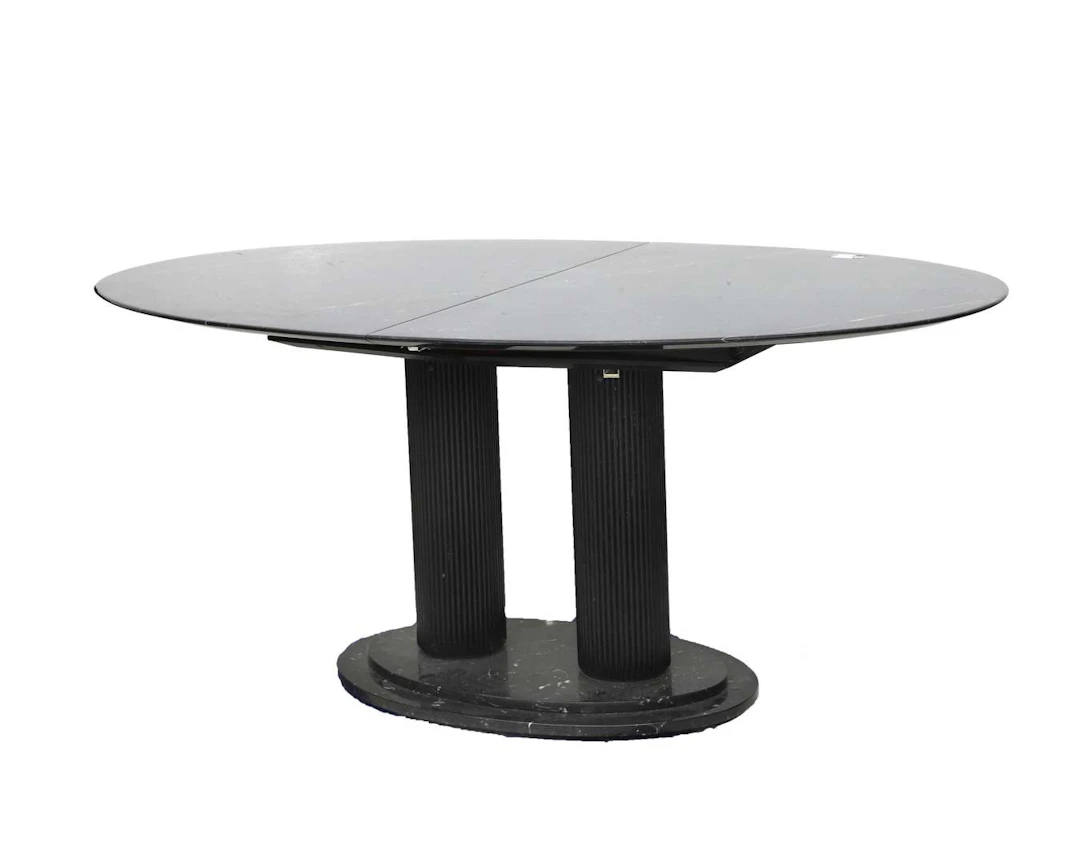 An oval extendable table with an oval black marble top and a wooden