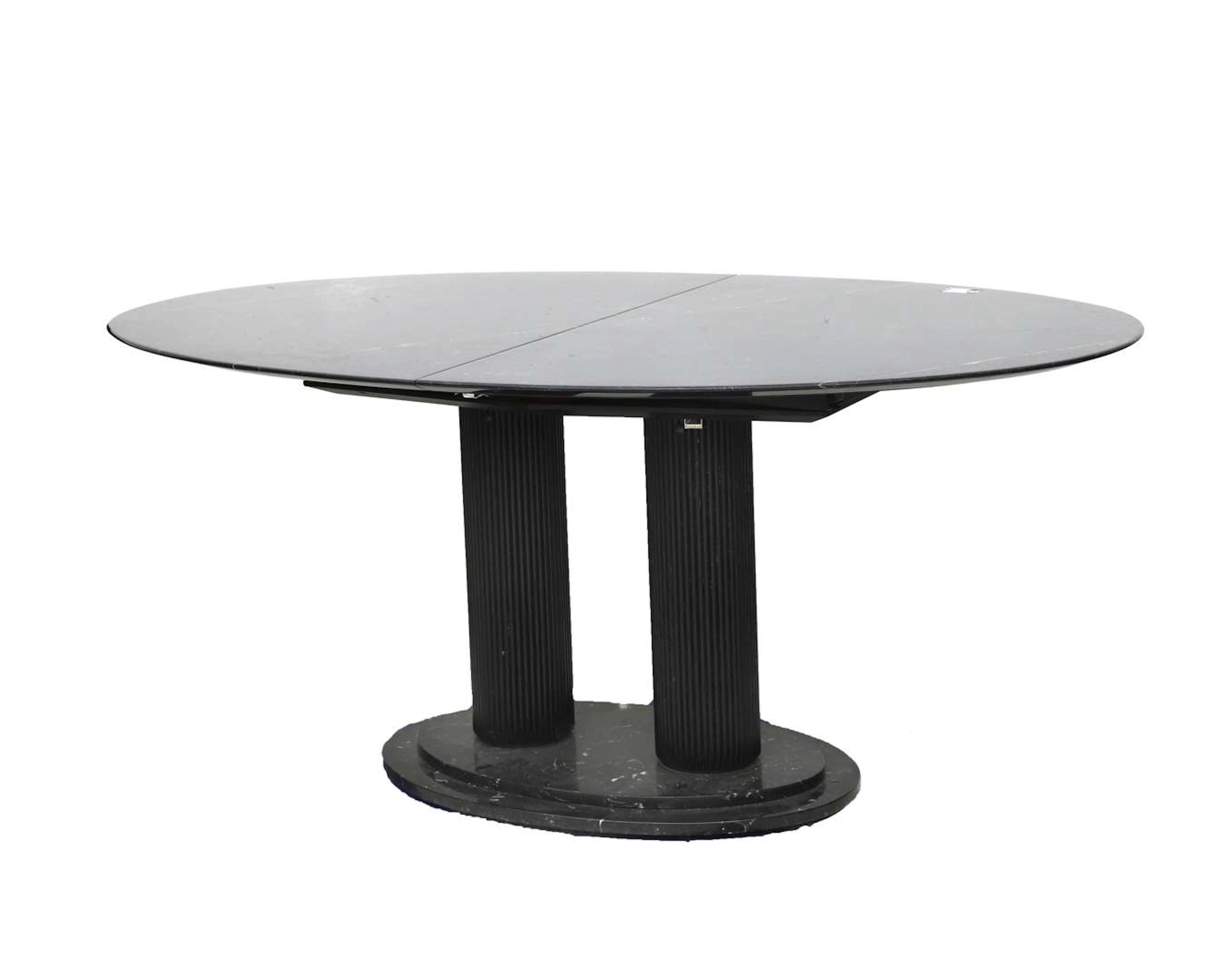 An oval extendable table with an oval black marble top and a wooden