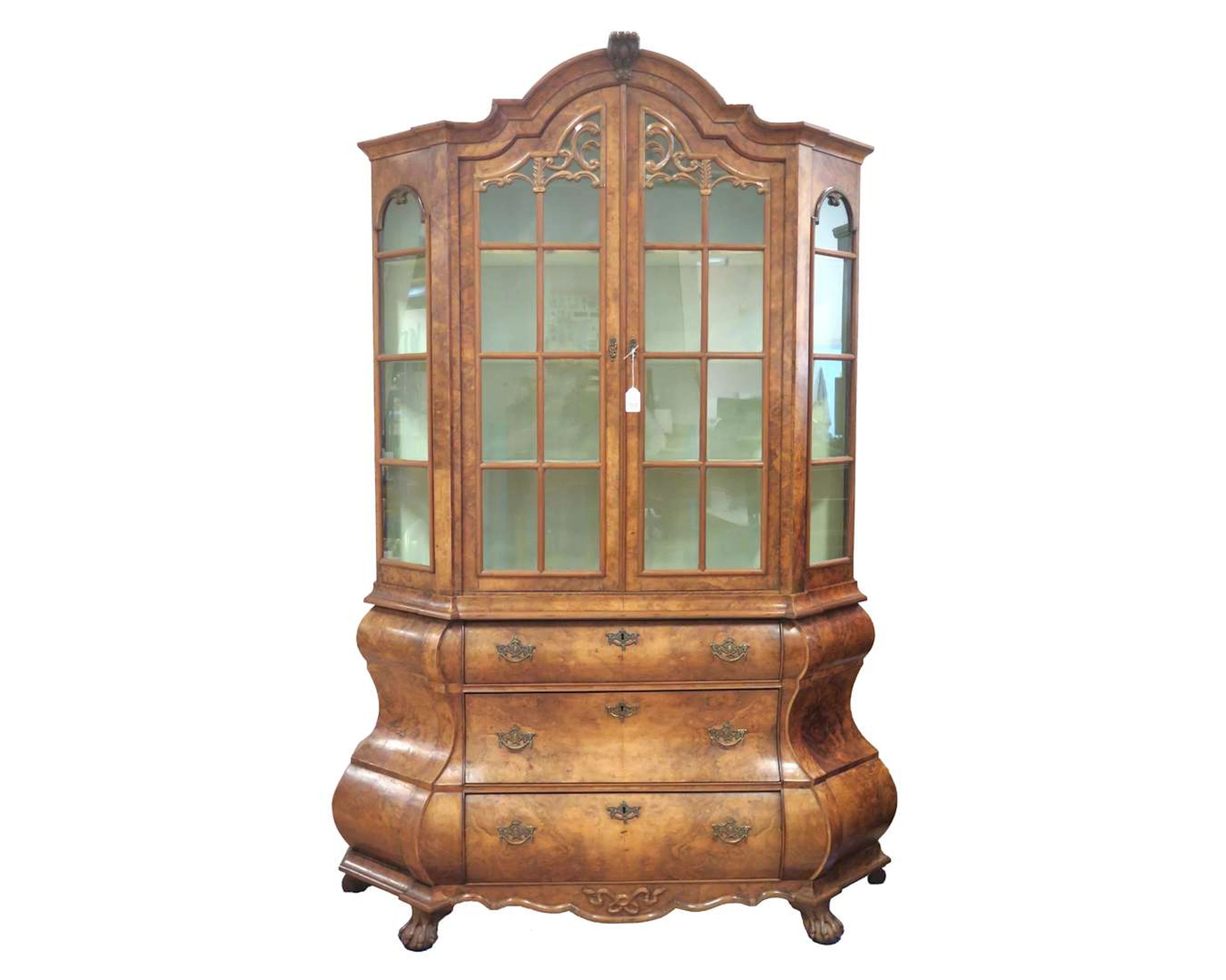 A walnut display cabinet with a crest and claw feet. 20th century