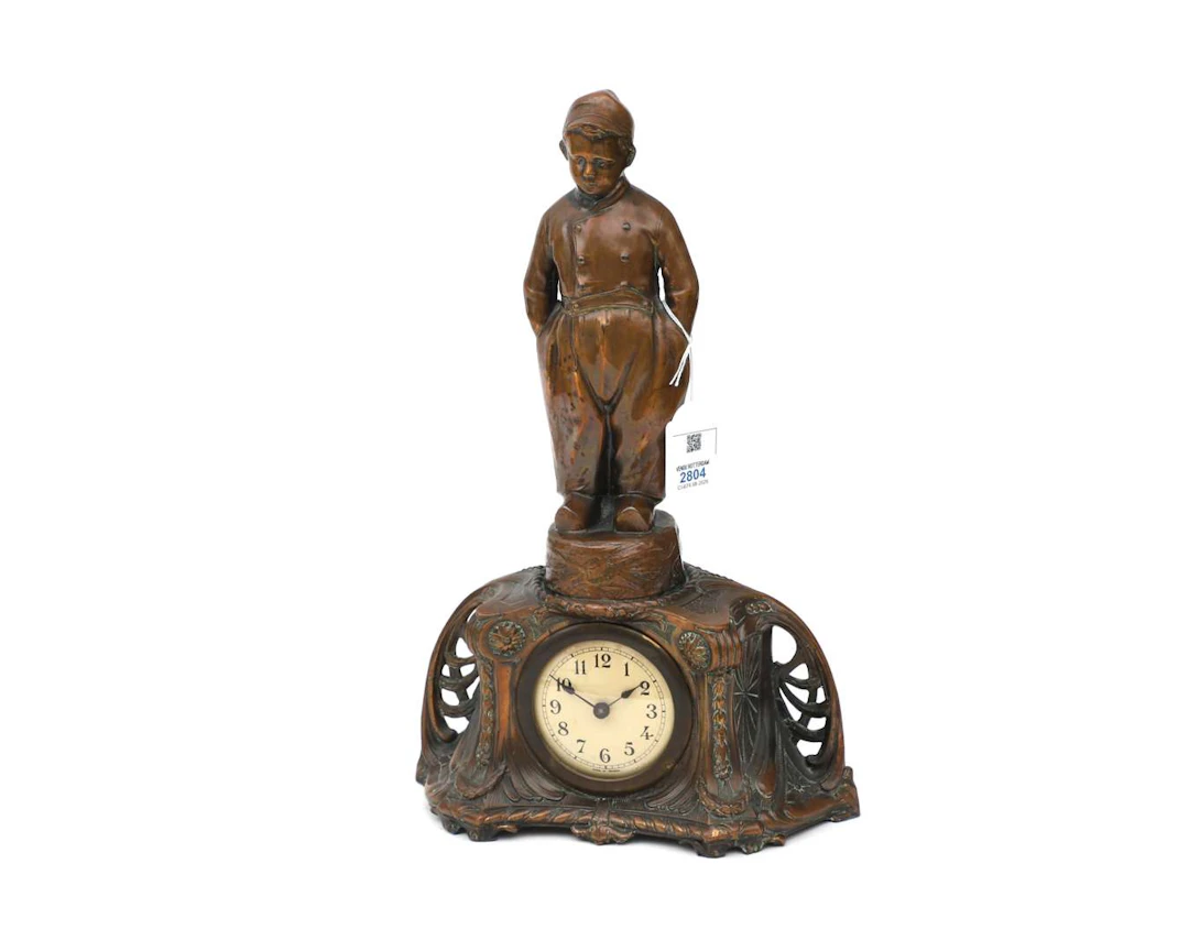 A bronze metal pendulum clock topped by a young farmer. France, circa 1900