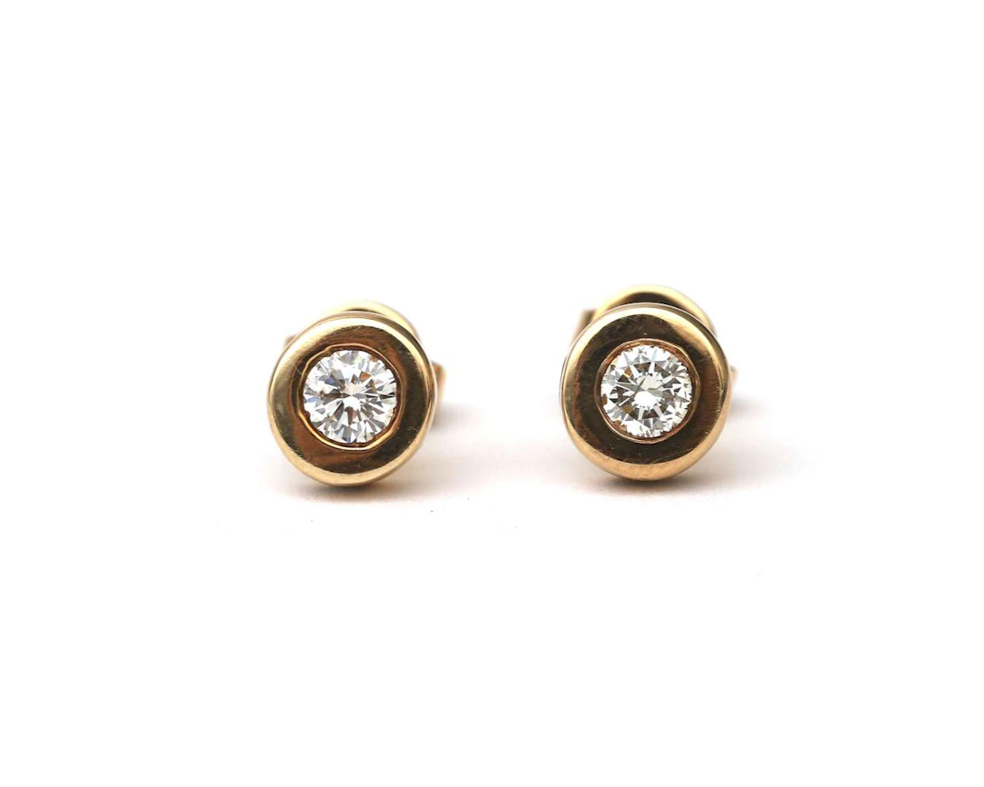 A pair of 14k yellow gold solitaire ear studs with diamonds