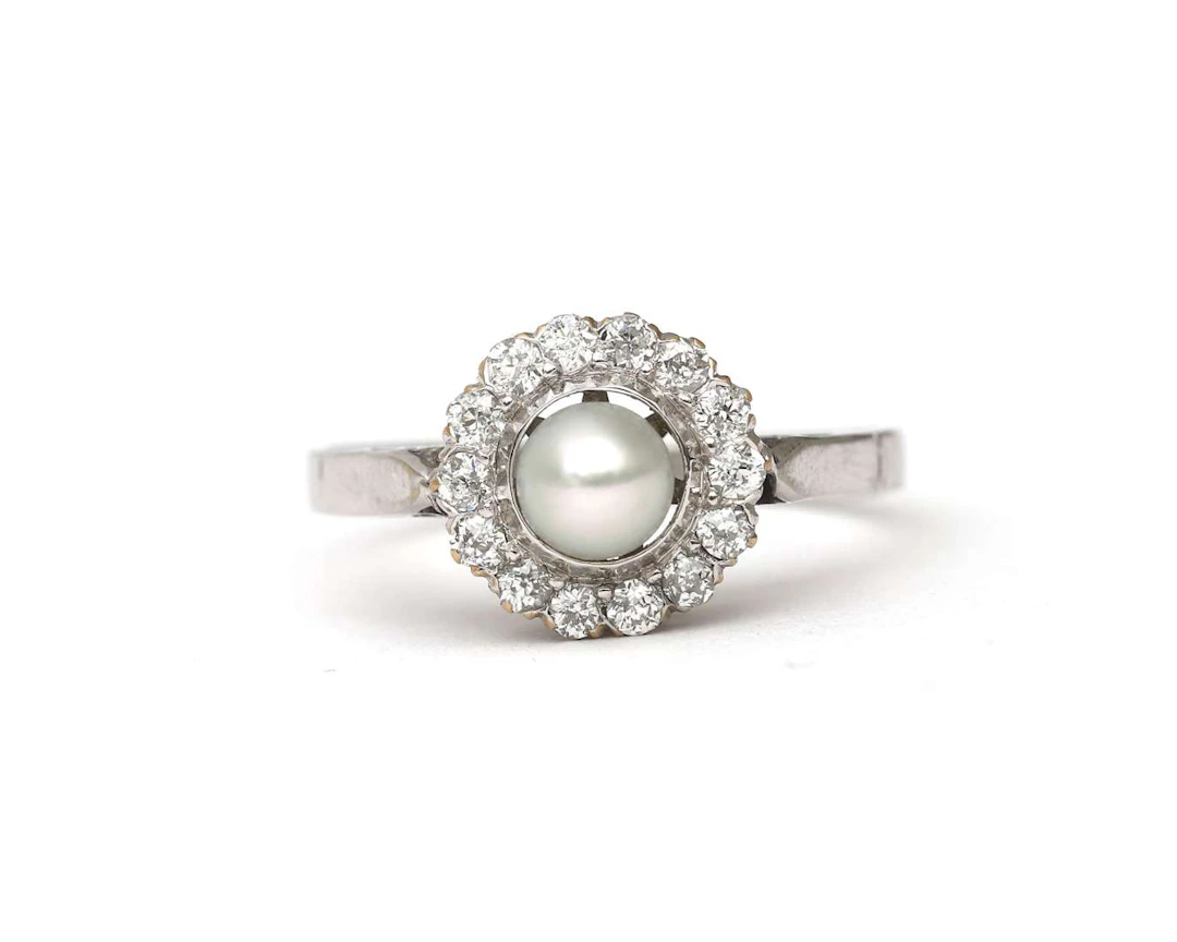 A 14k white gold ring set with a cultured pearl and a diamond