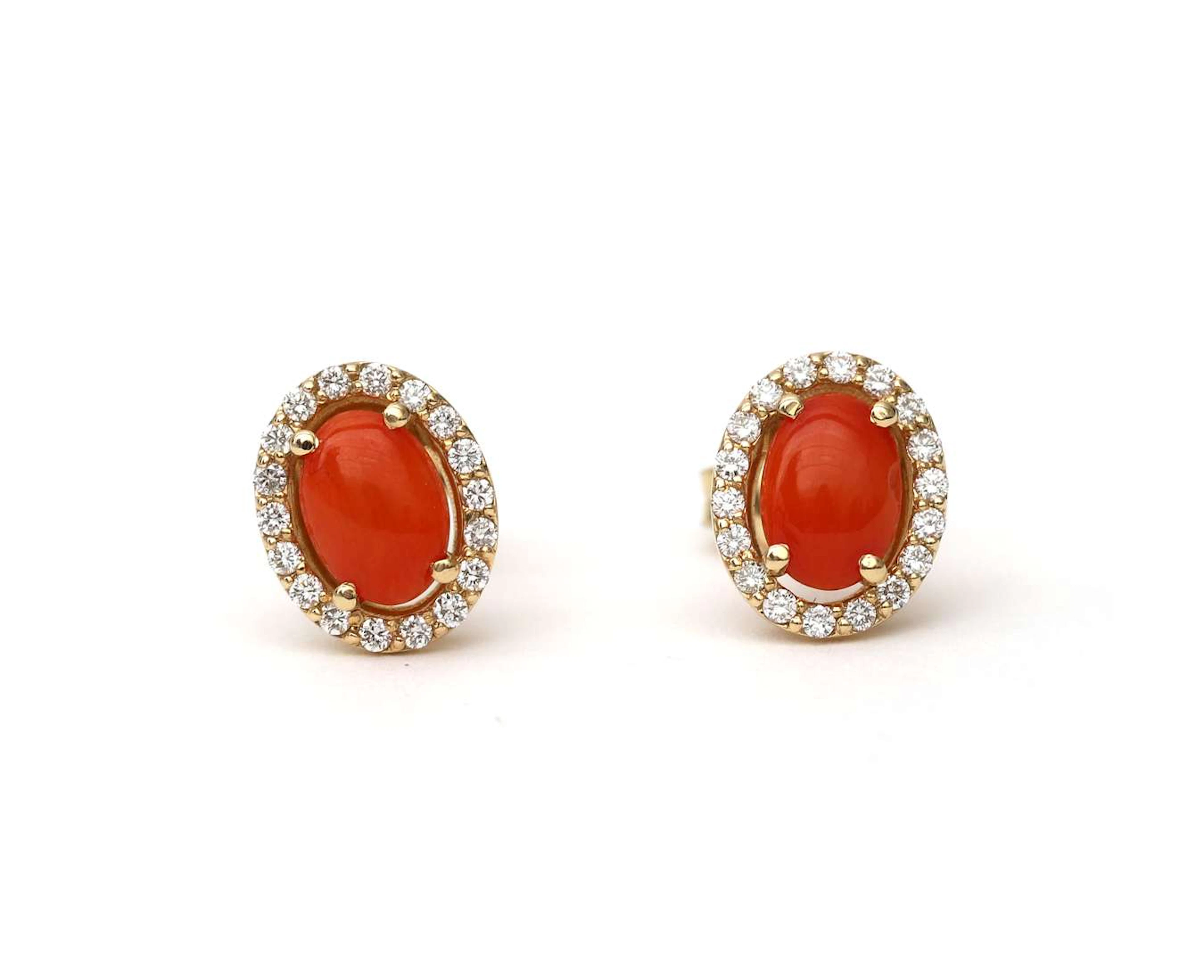 A pair of 14k yellow gold ear studs with red coral and diamonds