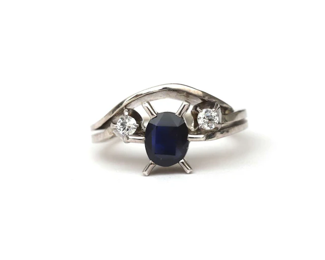 A 14-carat white gold ring set with a dark blue and white sapphire