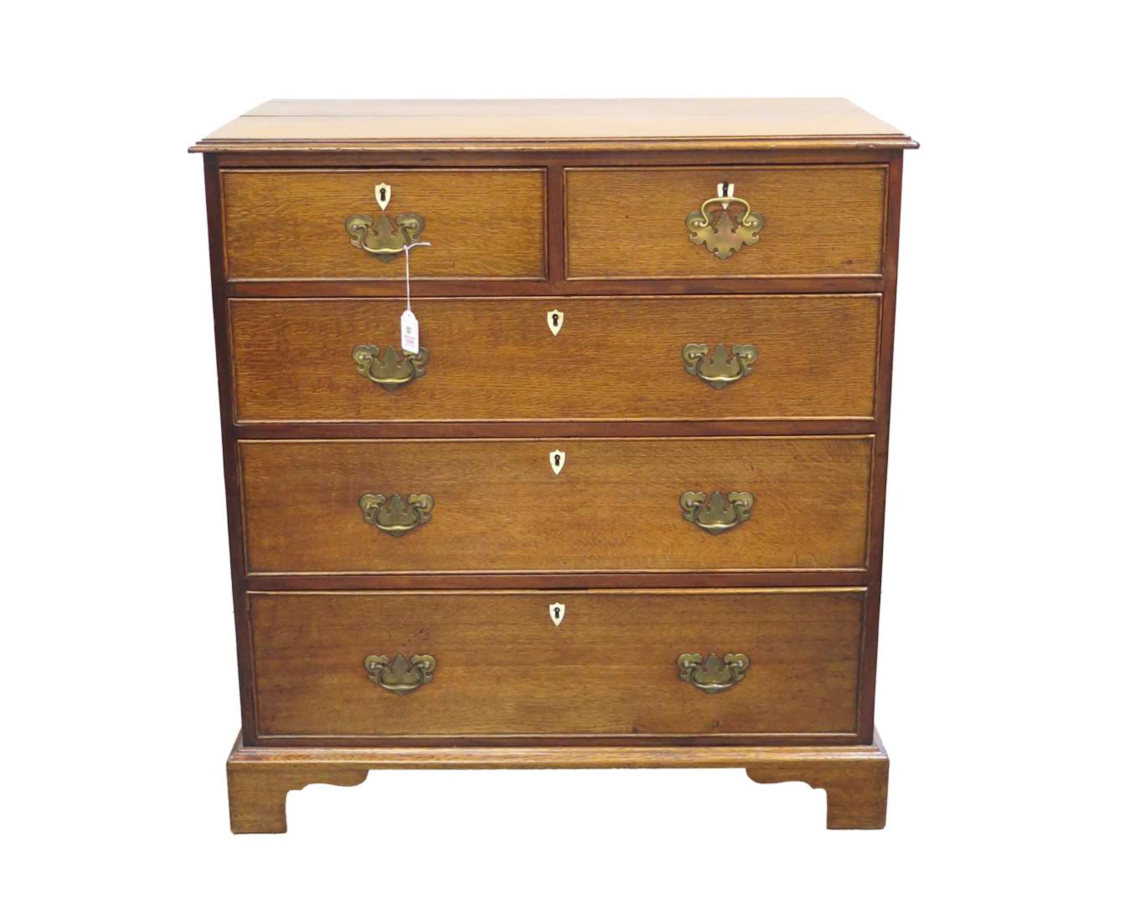 An oak chest of drawers with leg-mounted lock plates and brass fittings.