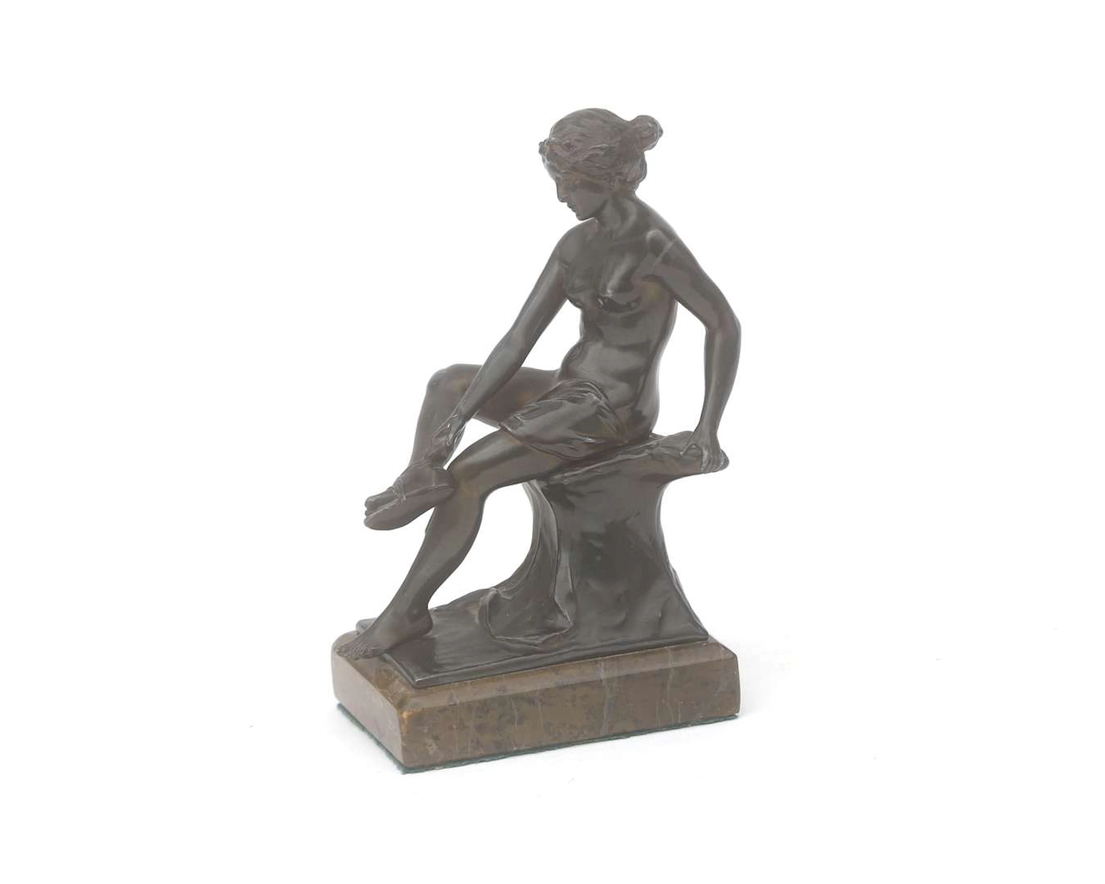 A bronze statue of a seated woman tying her sandals, free after Ernst