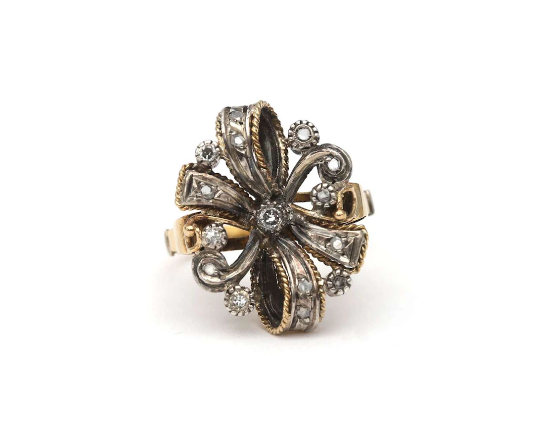 A 14k yellow gold ring with a silver bow and a diamond