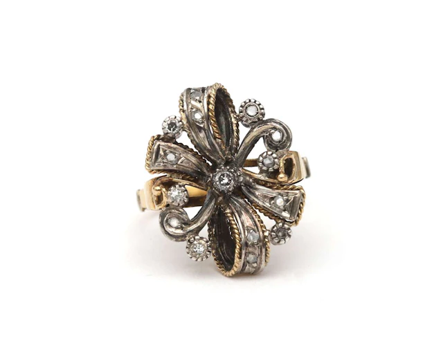 A 14k yellow gold ring with a silver bow and a diamond