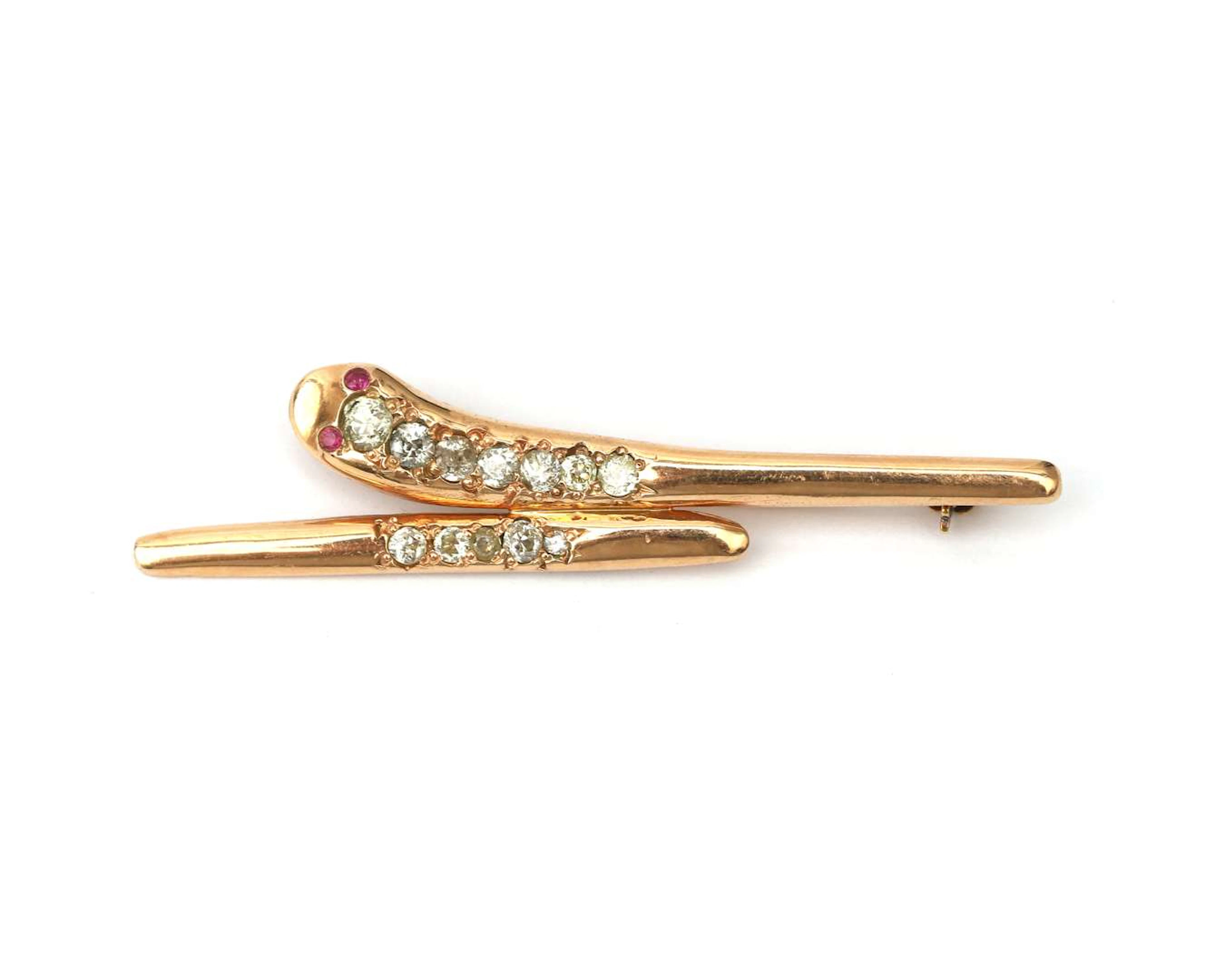 An 18k yellow gold stylised snake brooch set with a diamond and a ruby
