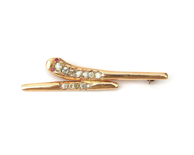An 18k yellow gold stylised snake brooch set with a diamond and a ruby