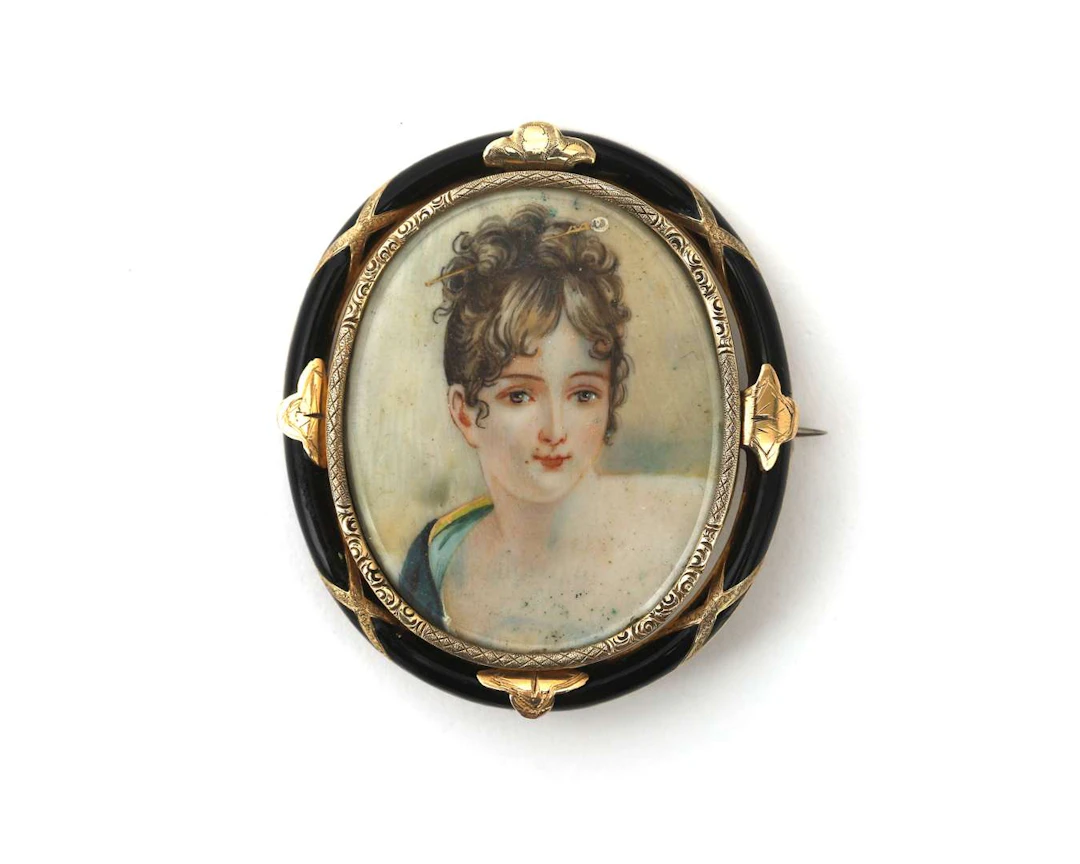 A 14k yellow gold brooch with a miniature