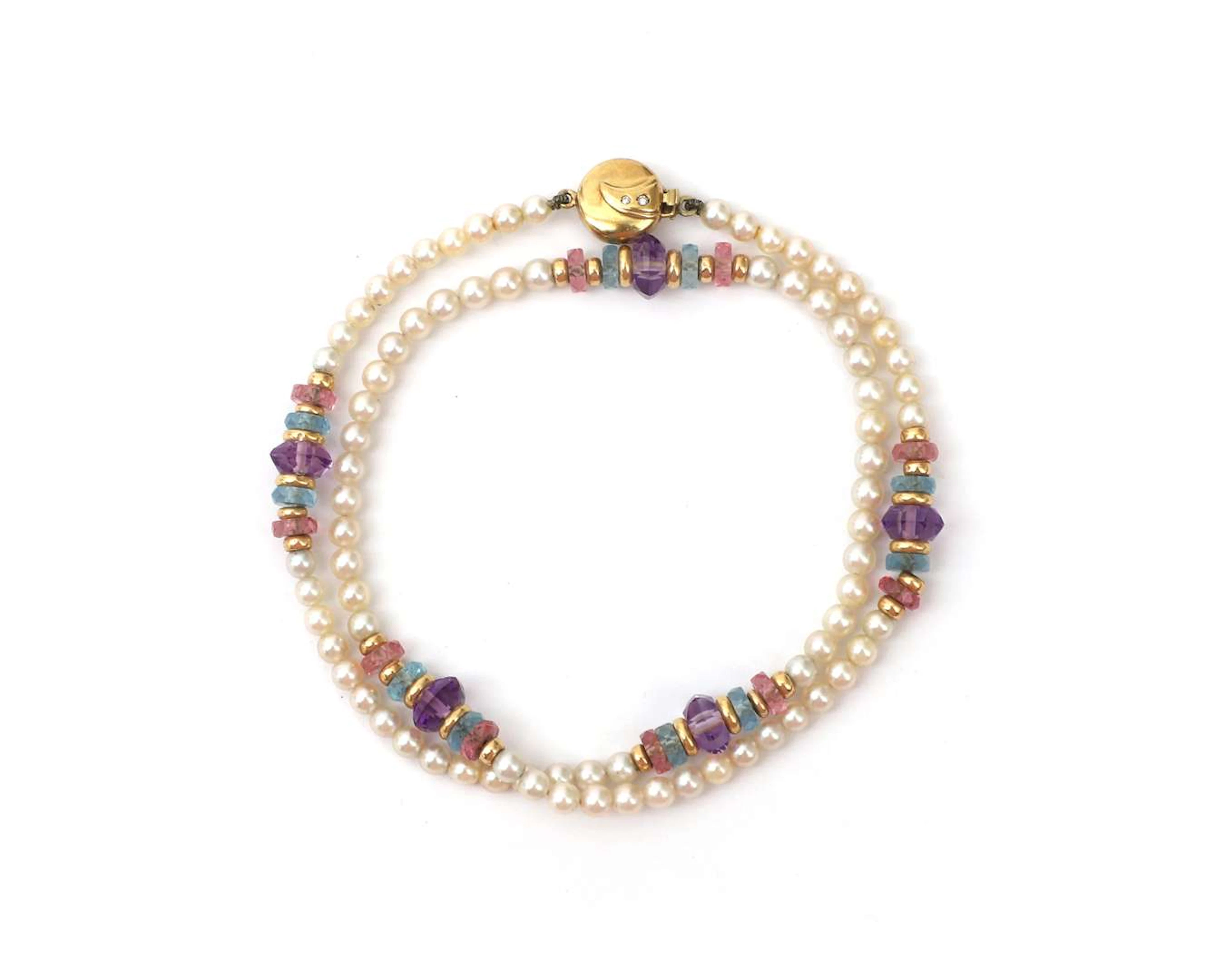 A pearl necklace with 14-carat yellow gold accents and gemstones