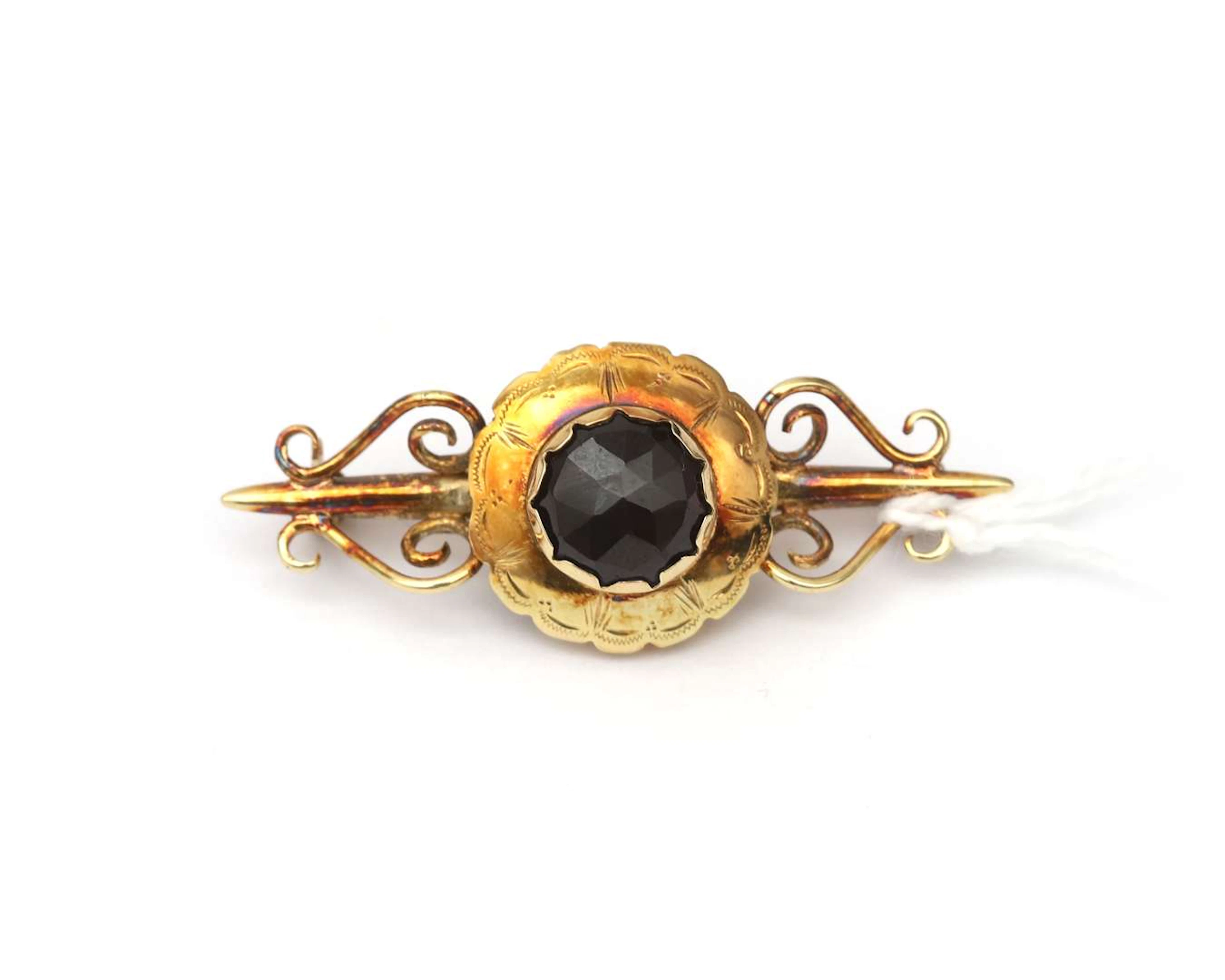 A 14k yellow gold brooch with a garnet