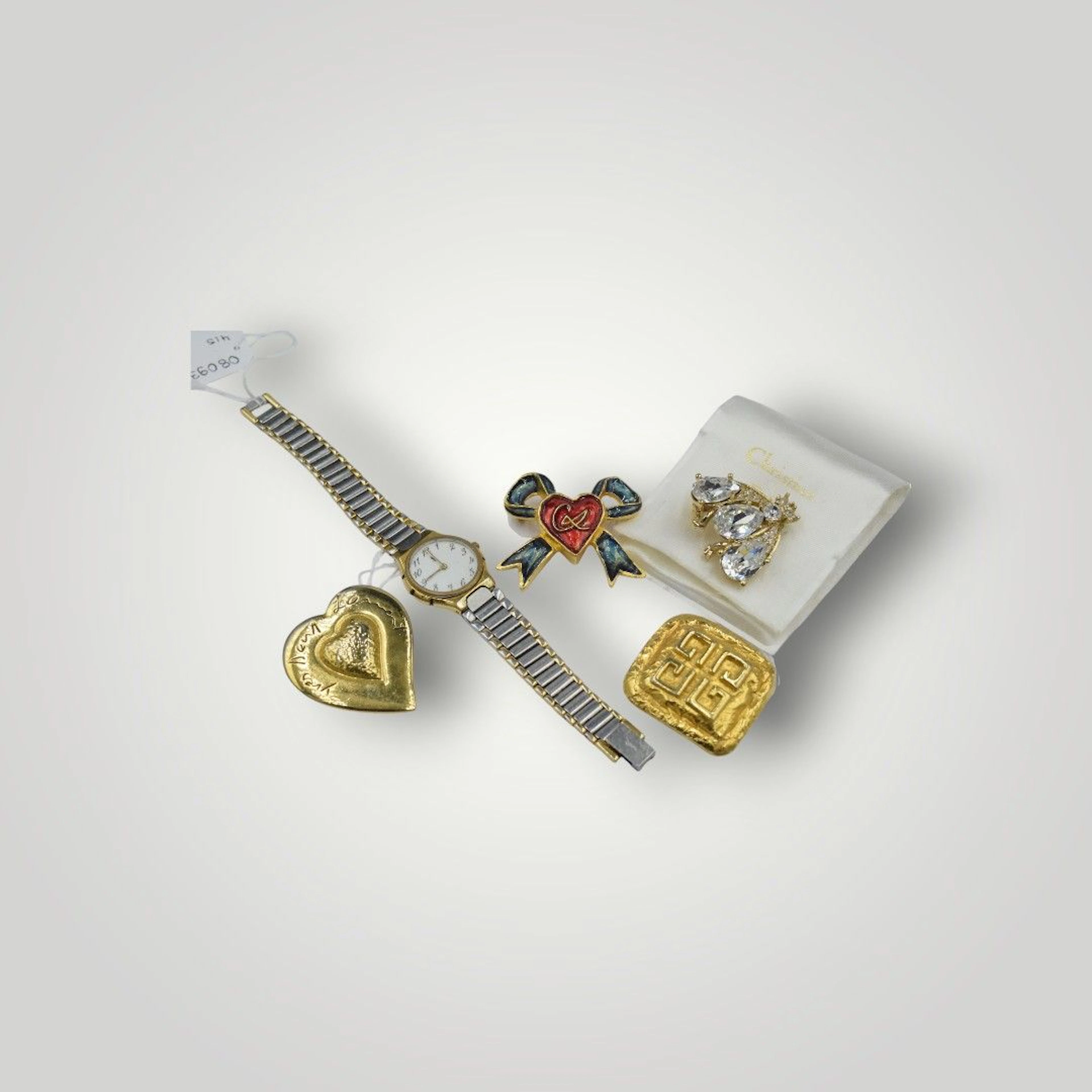 DIOR - CHRISTIAN LACROIX - YVES SAINT LAURENT- GIVENCHY PARFUM Ensemble comprenant quatre broches siglées au dos et une montre de dame en métal doré et argenté. Vendu en l'état