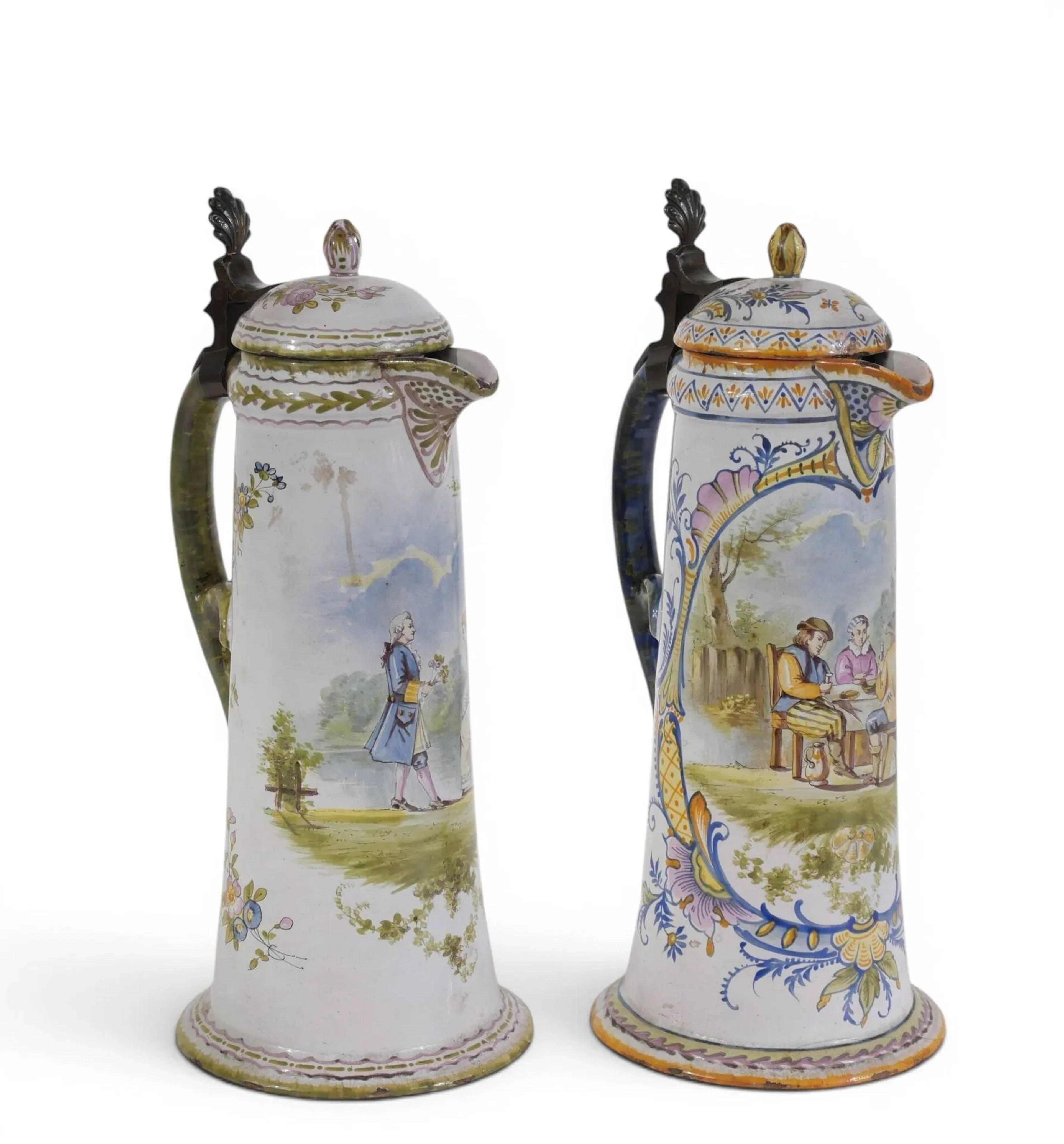 Deux grandes chopes en faïence au décor polychrome d'une scène galante pour la première et d'un déjeuner en extérieur pour la seconde et de motifs floraux Une marquée VP au dessous, l'autre AF (?) Charnières en étain H : 33 cm Eclats