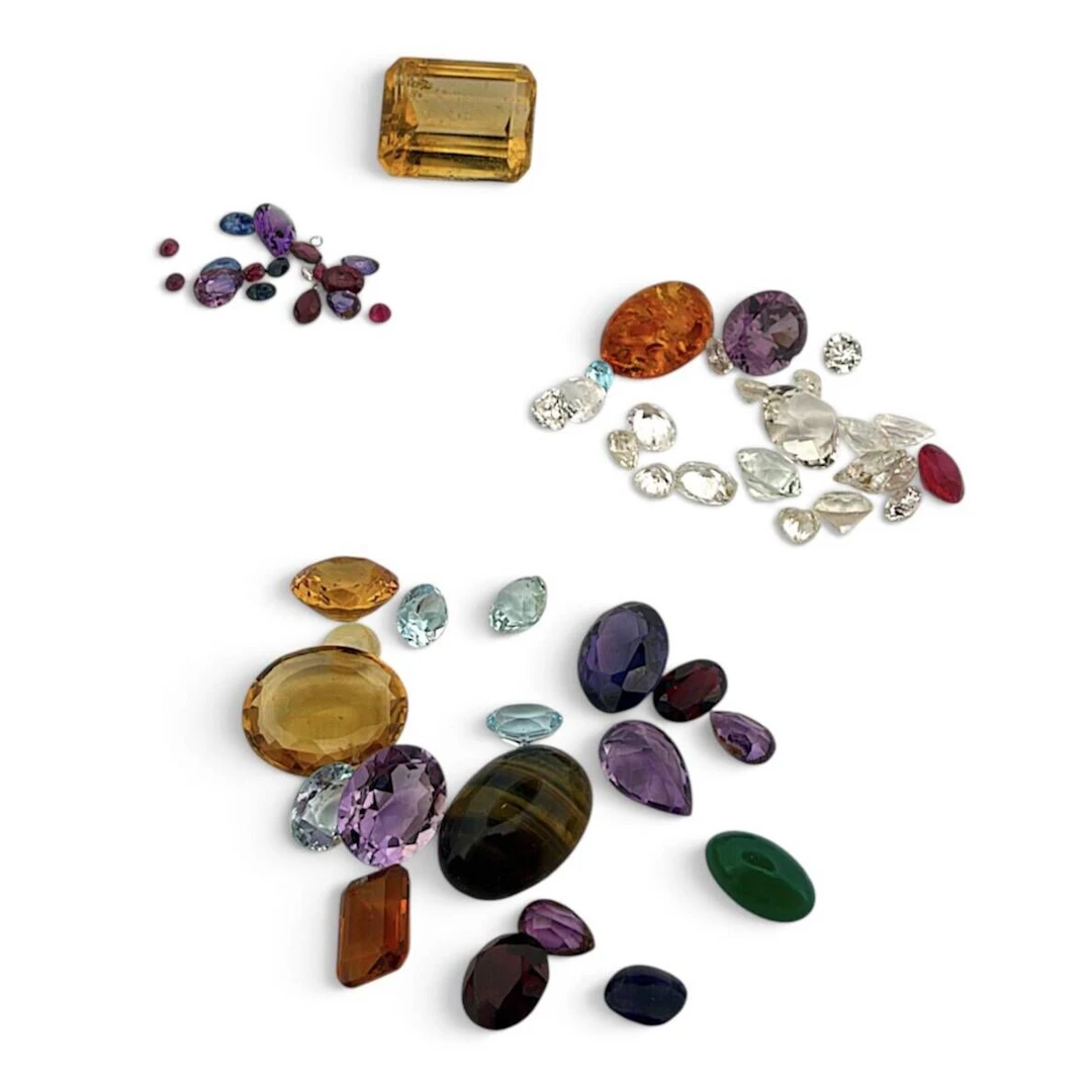 Assortment of gemstones on paper, including: sapphires, rubi - Lot 141