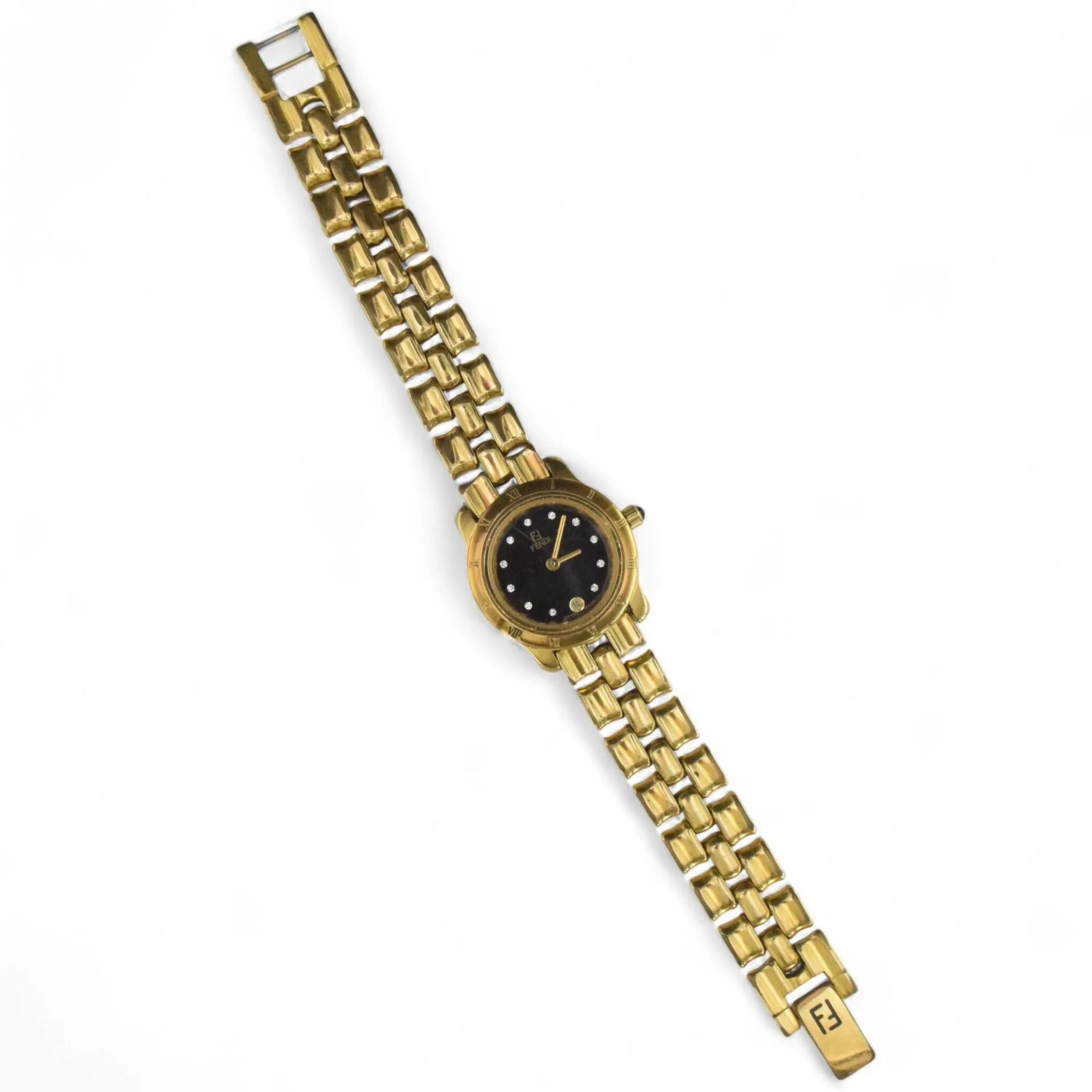 FENDI N°860 L Montre bracelet de dame en métal doré, cadran doré, index pierres blanches formant les heures, date par guichet à 6h, mouvement quartz (pile non vérifiée), bracelet intégré à boucle cliquet siglée. Diam. : 25 mm.