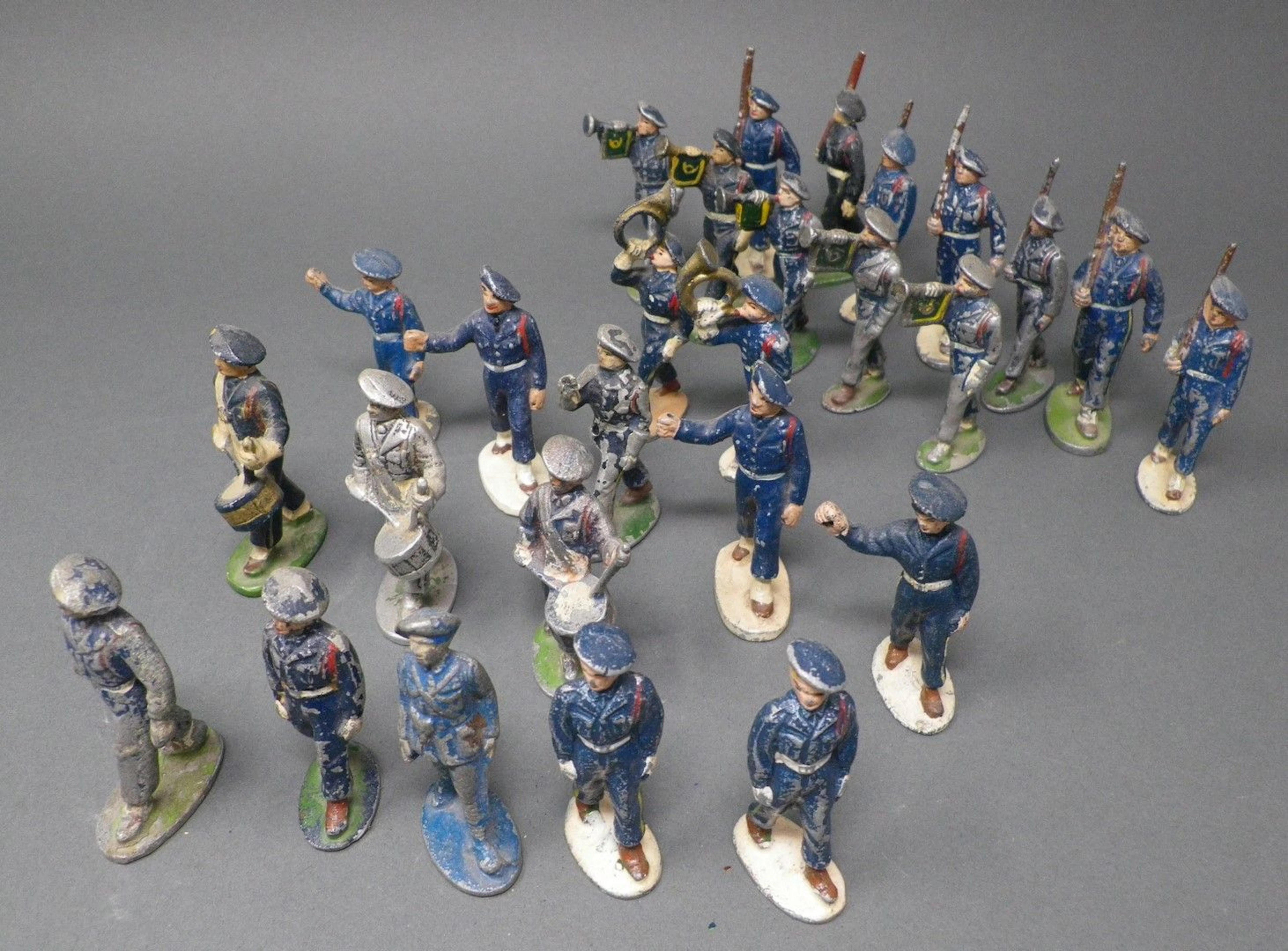 QUIRALU - Chasseurs au défilé (1945-1955) Vingt-sept figurines en bleu marine, pantalons et guêtres blanches dont : tambours, clairons, chasseurs fusil sur l'épaule, reproduits p. 31 - Bibliographie : Les jouets Quiralu 1933-1964 - R. Alazet - J. Borsarello - H. Giroud - Ed° J. Granchet Paris. Jouets anciens pouvant présenter des manques de peinture, des chocs ou des manques, y compris pour les conditionnements éventuels. Vendus en l'état et sans réclamations.