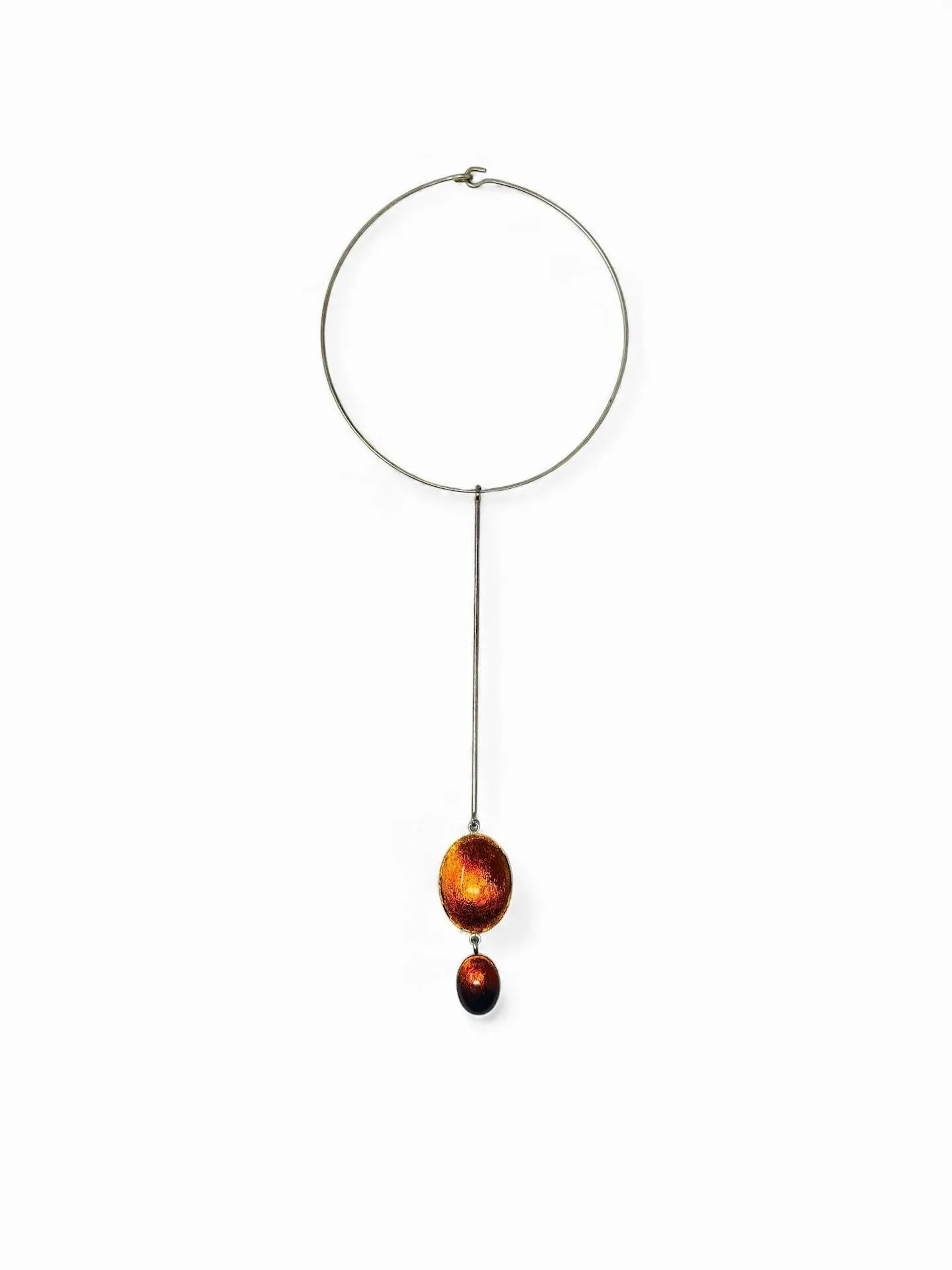 Philippe FERRANDIS Paris Collier torque en métal argenté retenant une tige à laquelle sont suspendus deux médaillons de tailles différentes et de forme ovale à fond plat agrémenté de verre teinté orange. Signé H. 34,5 cm
