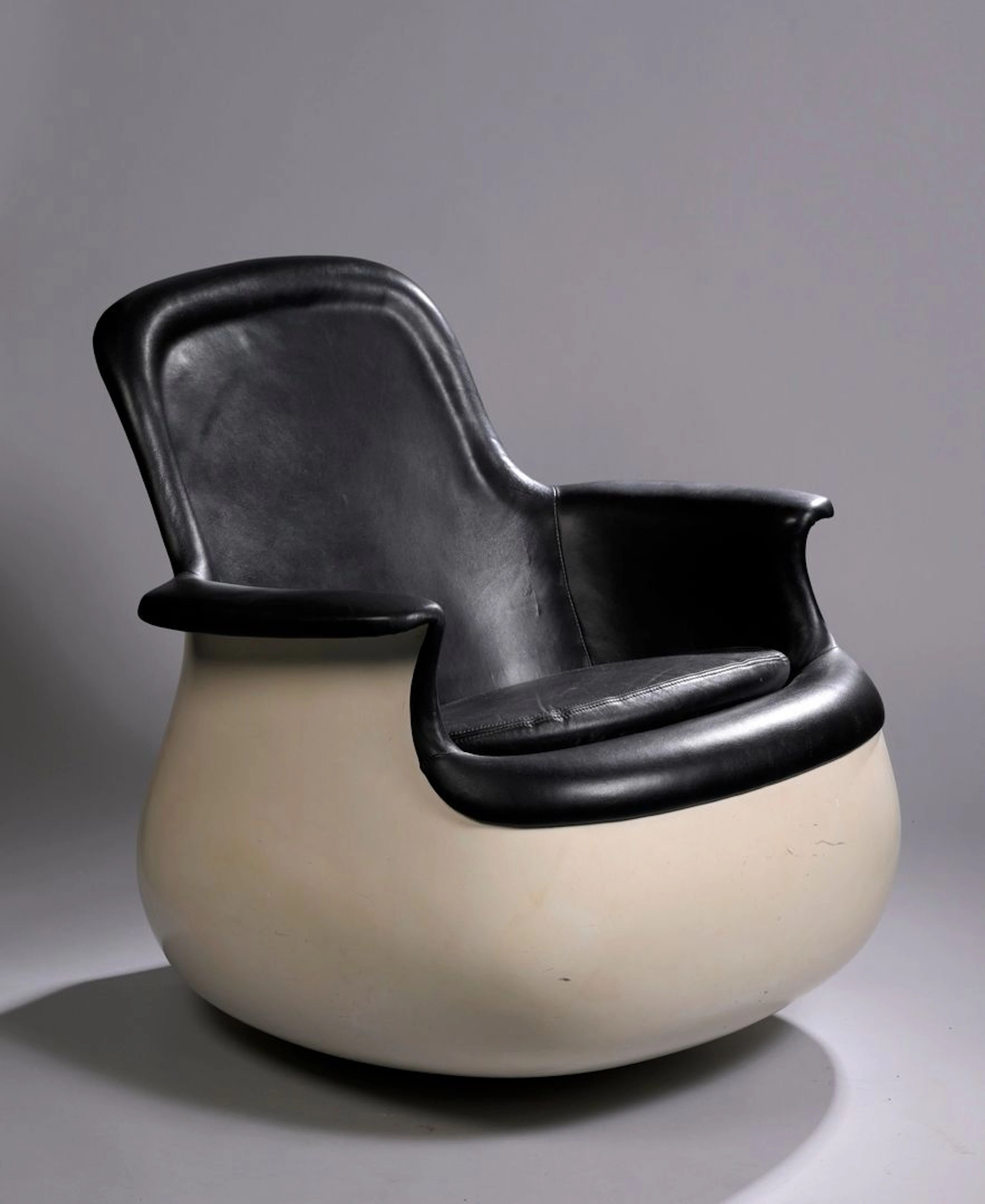 MARC HELD (1932) Fauteuil modèle Culbuto bas, circa 1970, basculant et pivotant en polyester renforcé de fibre de verre laqué blanc, dossier arrondi et base convexe, recouvert d’un cuir noir. H. : 71 cm. - L. : 73 cm. - P. : 69 cm (Rayures, usures, cuir non d’origine) Edition Knoll BIBLIOGRAPHIE : - Charlotte & Peter Fiell, 70s Decorative Art, Edition Taschen, 2000, modèle similaire reproduit p. 404. - Gilles de Bure, Mobilier Français 1965-1979, Edition Du Regard, 1983, modèle similaire reproduit p.56. - Catalogue de l’exposition, Design Français 1960-1990, Edition Centre Georges Pompidou, 1988, modèle similaire reproduit p. 223.