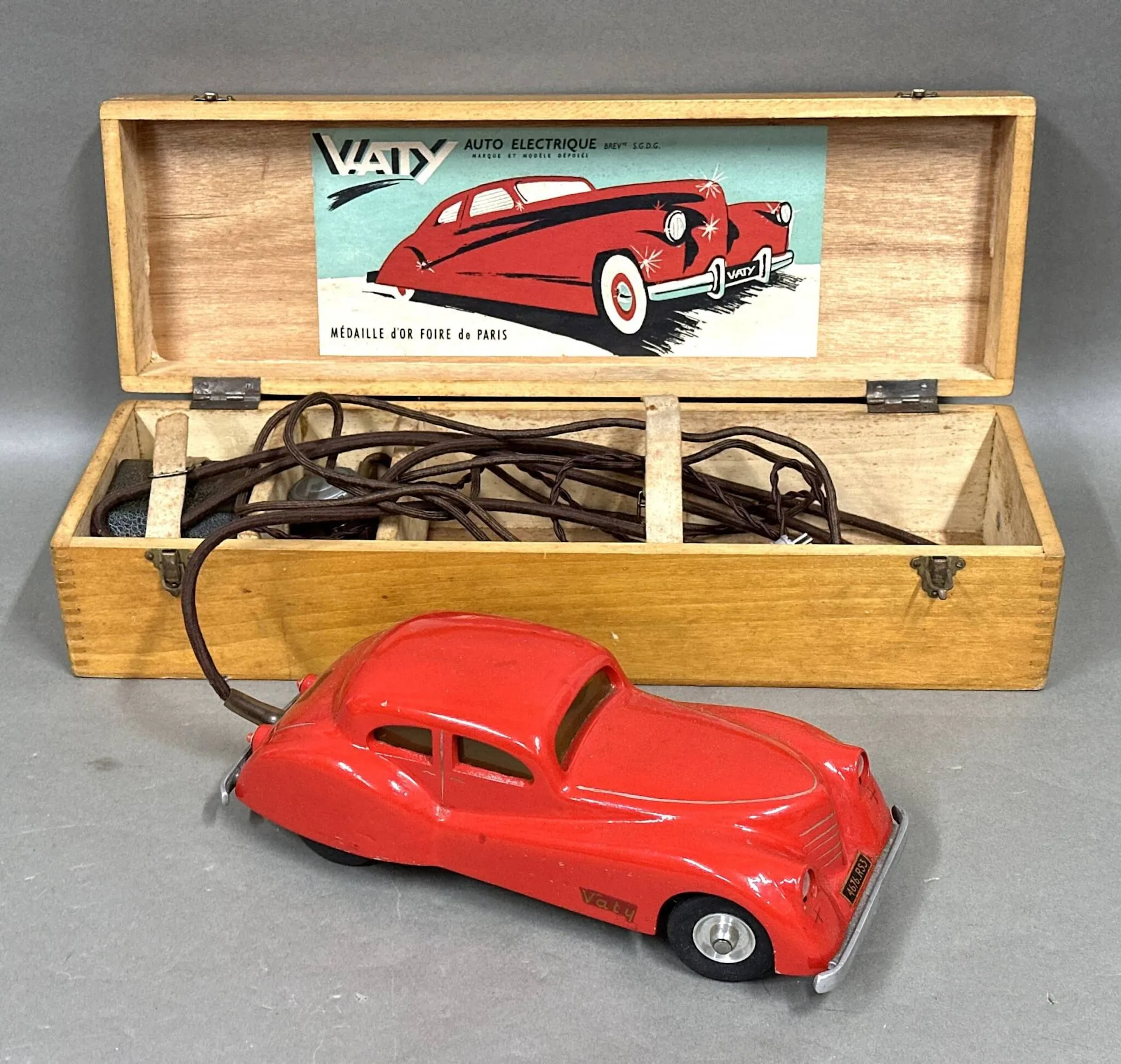 VATY auto électrique Coupé grand sport en métal rouge, avec transformateur et volant électrique. Boîte d'origine en bois. L. 31 cm. Ce jouet fût breveté et a remporté la Médaille d'or à la Foire de Paris (circa 1955). Très bel état. Non testé.