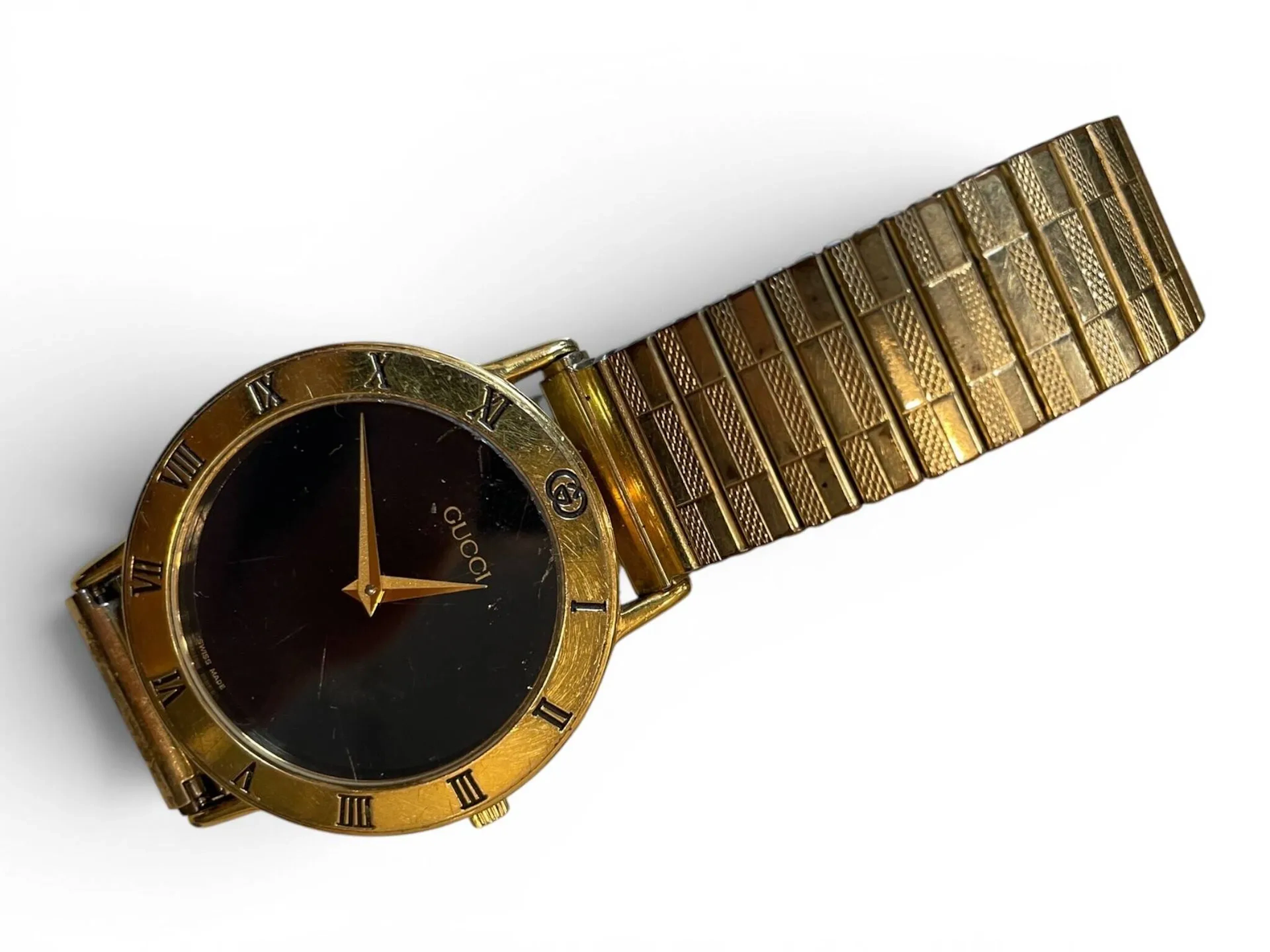 GUCCI Montre bracelet en plaqué or à cadran noir et aiguilles type Dauphine, lunette gravée de chiffres romains pour les heures. Fond de boîtier clipsé en plaqué or signé et numéroté. Mouvement à quartz Diam. 31 mm Usures et rayures