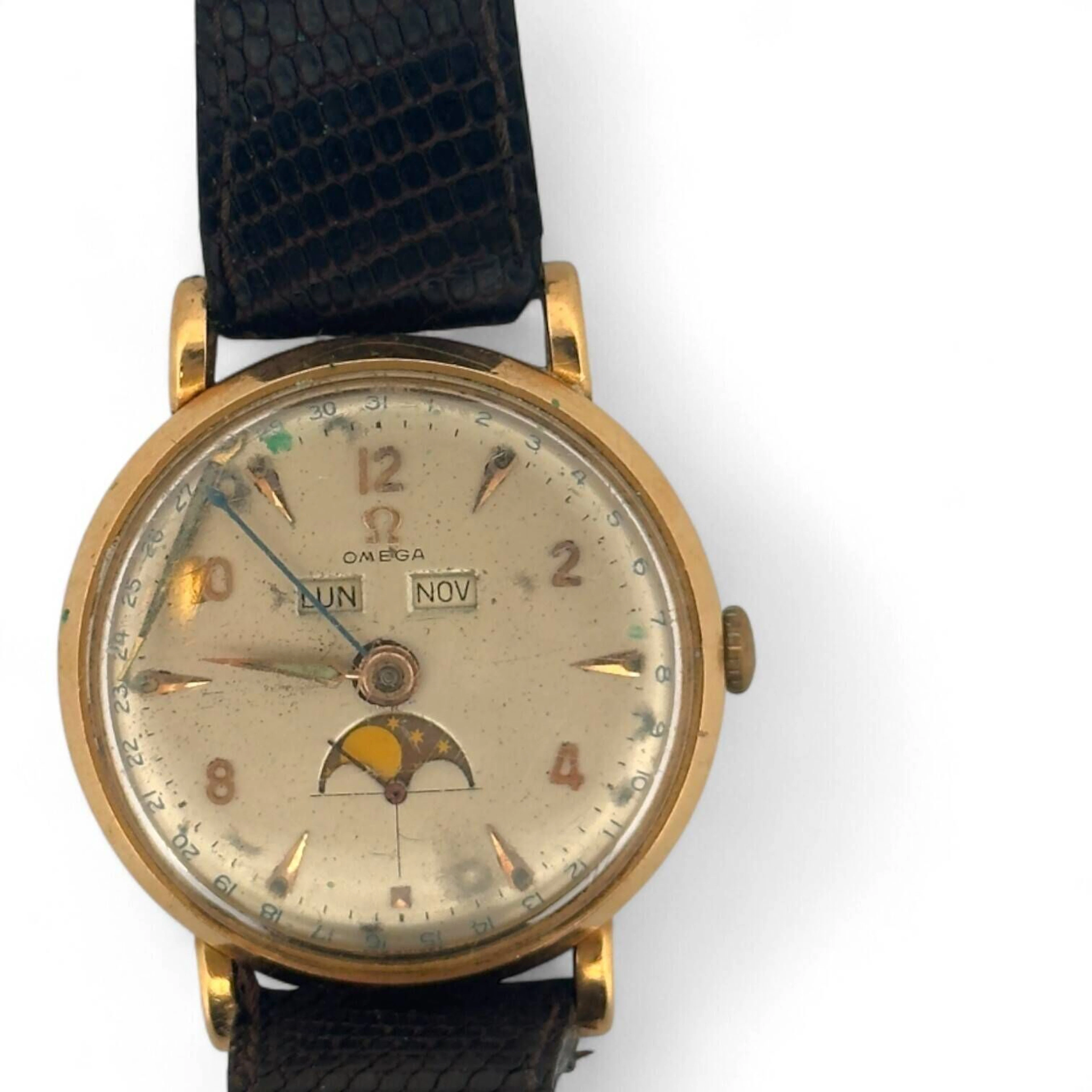OMEGA COSMIC TRIPLE DATE Montre-bracelet en or 18K (750 millièmes), cadran argenté, index flèches et chiffres arabes en appliques dorées, aiguilles« Alpha » dorées, date par aiguille centrale bleue, jour et mois par guichets à midi, phase de Lune et petite seconde à six heures. Fond clipé en or 18K (750 millièmes). Mouvement mécanique à remontage manuel signé Omega, calibre 381, numéroté 11206053. Bracelet en cuir, boucle ardillon en métal. Montre non fonctionnelle lors de l’expertise, sans garantie de fonctionnement futur et d’état des pièces. Importantes rayures, marques au boitier, marques au cadran avec légers enfoncements, aiguilles des minutes désolidarisée. Vers 1960 Poids brut 45,5 g Diamètre 34 mm