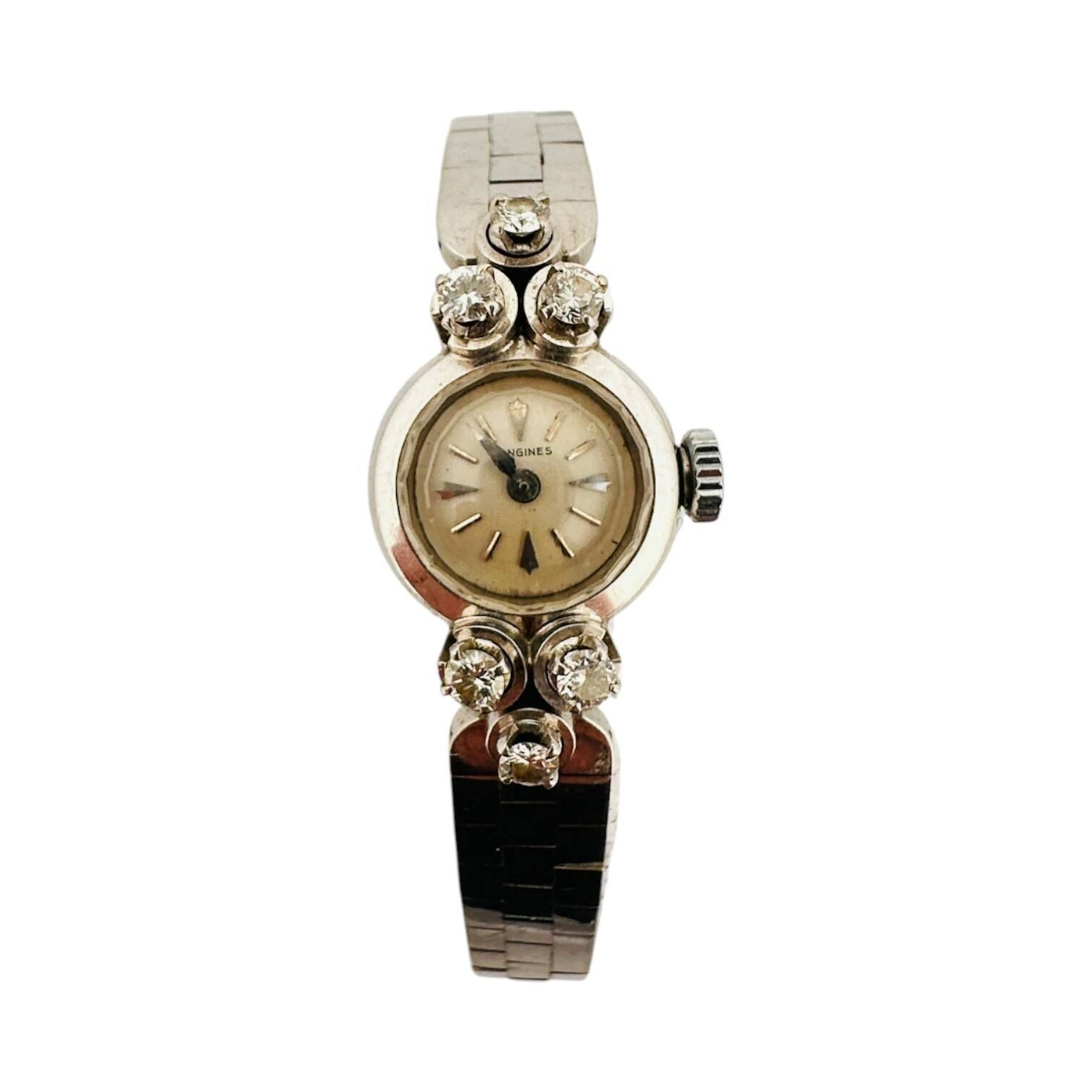 LONGINES Montre bracelet de dame en or gris 18K (750 millièmes), cadran argenté, index en appliques argentées, aiguilles type Alpha facettéesargentées. Fond clipé en or gris 18K (750 millièmes). Mouvement mécanique à remontage manuel signé LONGINES, calibre 13.50. Anses serties de diamants taille brillant. Bracelet en or gris 18K (750 millièmes) à mailles briques, fermeture à cliquets. Montre fonctionnelle lors de l’expertise, sans garantie de fonctionnement futur et d’état des pièces. Légères rayures au boitier et au bracelet. Travail français vers 1955 Poids brut 27,7 g Diamètre15mm, pour un poignet d’environ 16 cm