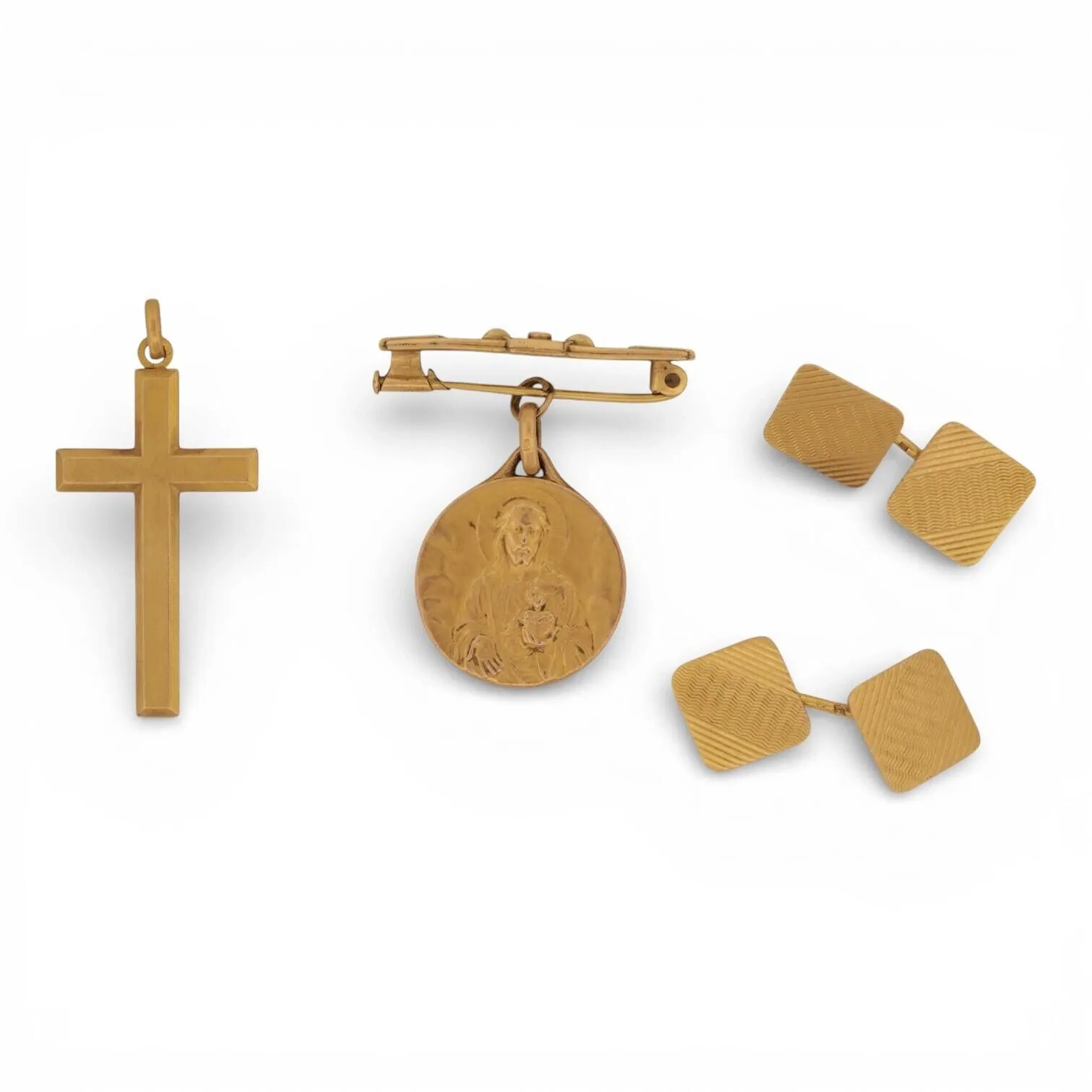 Paire de boutons de manchettes en or 18K (750) de section carrée à décor guilloché. Travail français. Poids : 5.30 g. On y joint un pendentif croix et une broche retenant une médaille religieuse en métal doré.