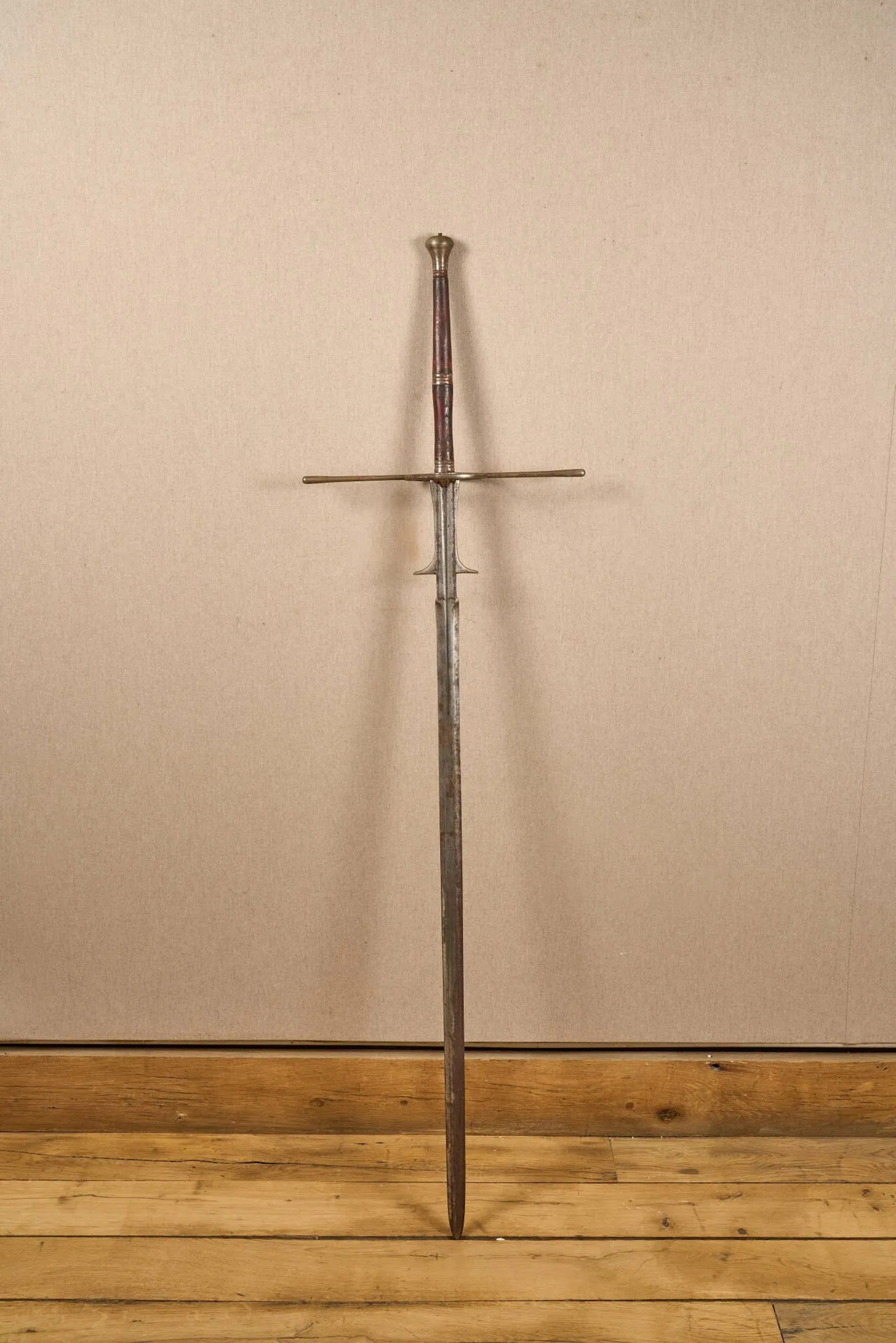 Épée à deux mains type montante. Monture en fer. Pommeau piriforme, pièce de garde à deux anneaux et quillons droits. Fusée en bois tourné. Forte lame à ricasso, deux ergots puis à méplat et double tranchant. Longueur totale : 156 cm. Travail de style XVIe siècle, probablement Violet le Duc