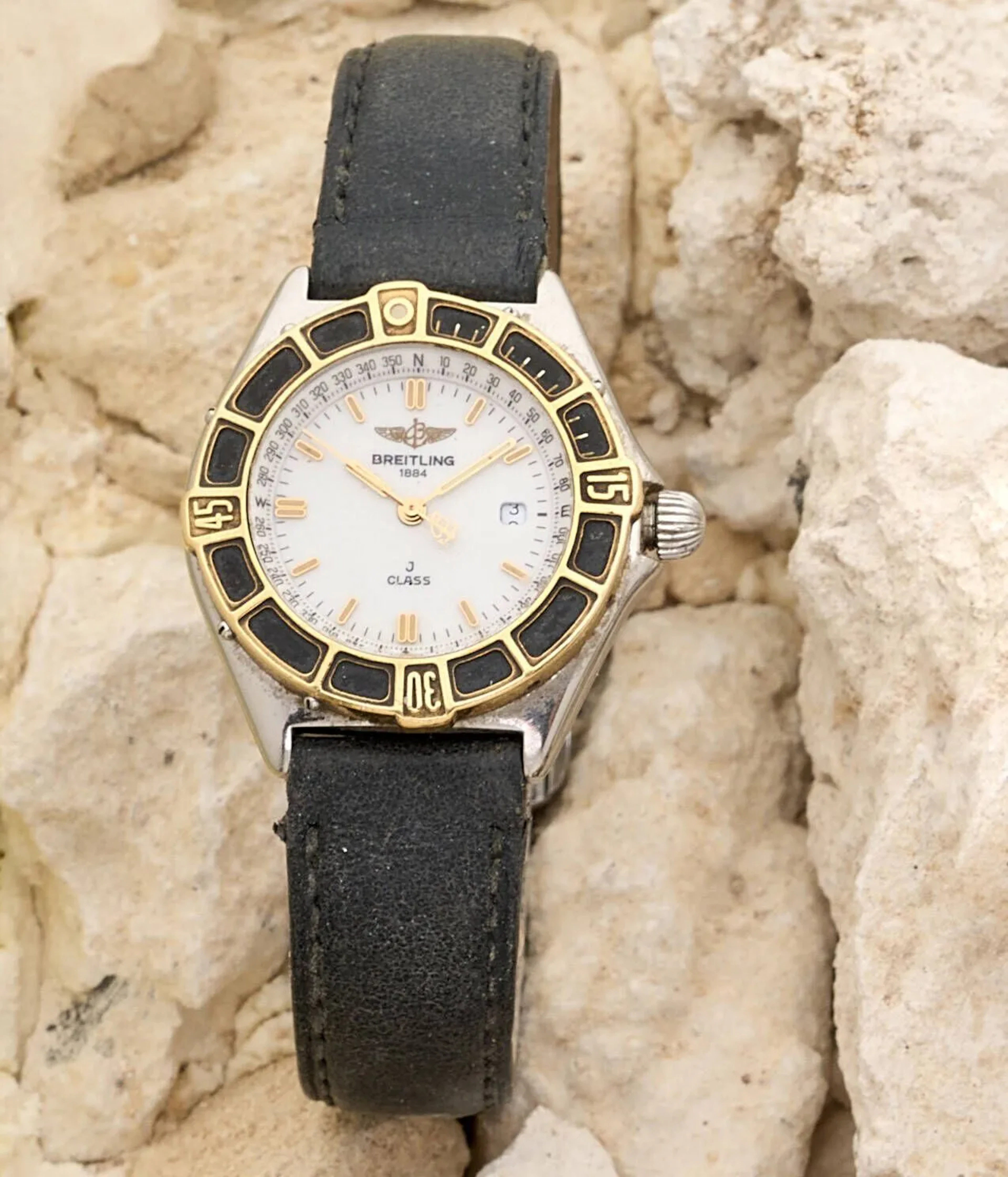 BREITLING J CLASS Montre-bracelet de dame en acier, cadran blanc laqué, minuterie traits noirs, index des heures en appliques dorées «baignoires» et luminescentes, rehaut avec indication de position, aiguilles baignoires dorées luminescentes, date à trois heures. Lunette tournante en acier doré avec repères. Fond en acier vissé signé Breitling référence D52063, numéroté 12575052064. Mouvement à quartz signé Breitling. Bracelet en cuir noir, boucle ardillon en acier métal. Montre non fonctionnelle lors de l’expertise, sans garantie de fonctionnement futur, état des pièces non garanti. Rayures au boitier, quelques traces à la lunette. Diamètre 30 mm Vers 2000 Expertise : Nicolas Amsellem
