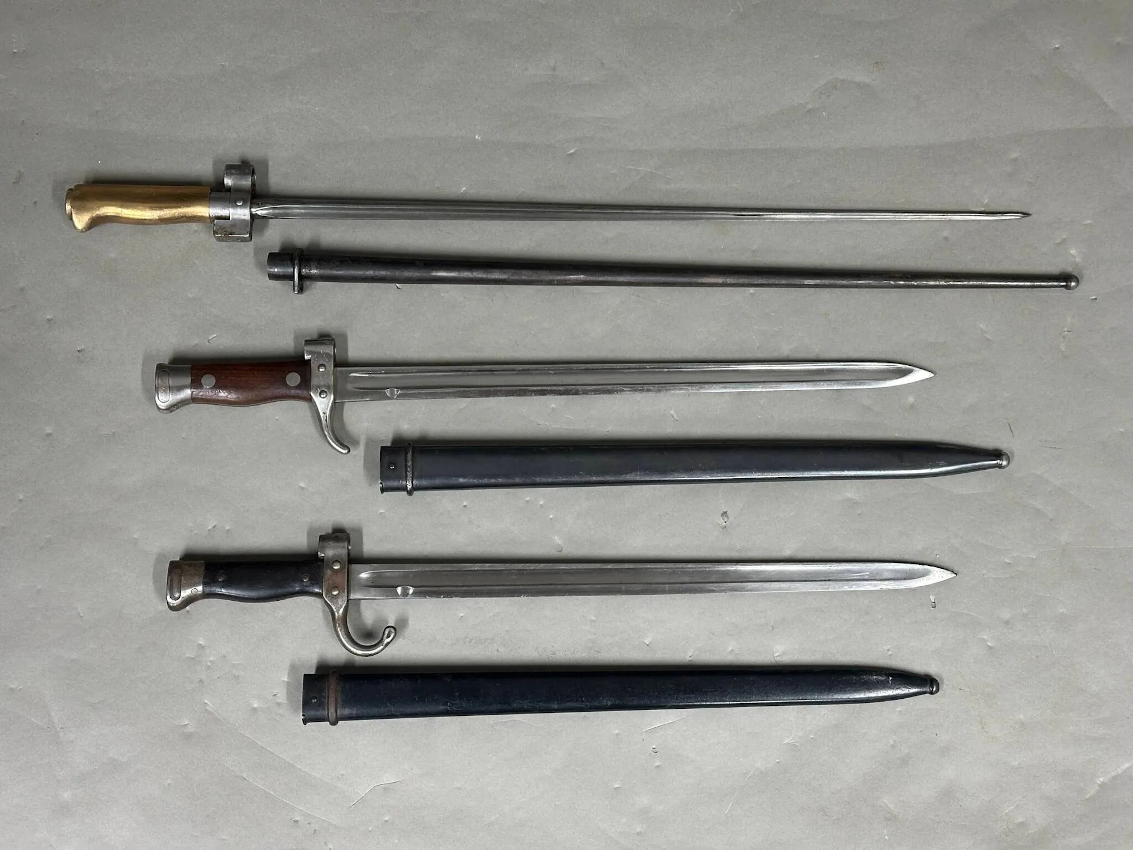 Trois baïonnettes françaises : - modèle Lebel 1886, lames cruciformes, sans quillon, à poignée en laiton. Croisière n° R 32 768. L. : 65 cm. - modèle Berthier. Mono matricule : croisière et fourreau n° 91727. L. : 51 cm. - modèle Berthier, plaquette en bakélite. Croisière n° 23451. L. : 51 cm. Traces d'oxydation.