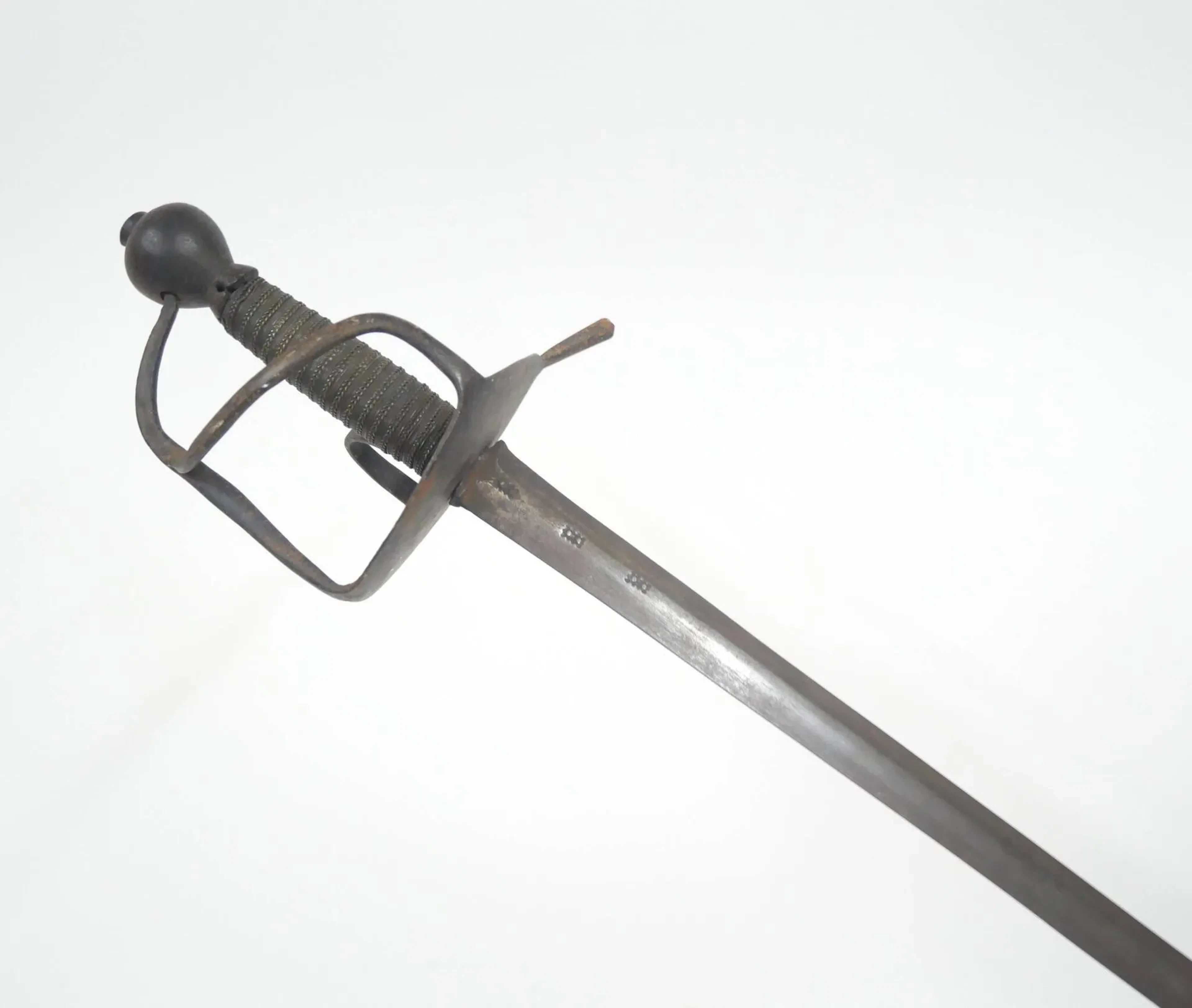 Épée de cavalerie, modèle dit à la wallonne. Pommeau piriforme et fusée en bois recouverte d’un double filigrane alterné. Plateau dont se détachent le quillon, poucier, arc de jointure et une branche secondaire. Longue lame à méplat et poinçons au talon. Longueur totale : 108 cm. Travail de la seconde moitié du XVIIe siècle.