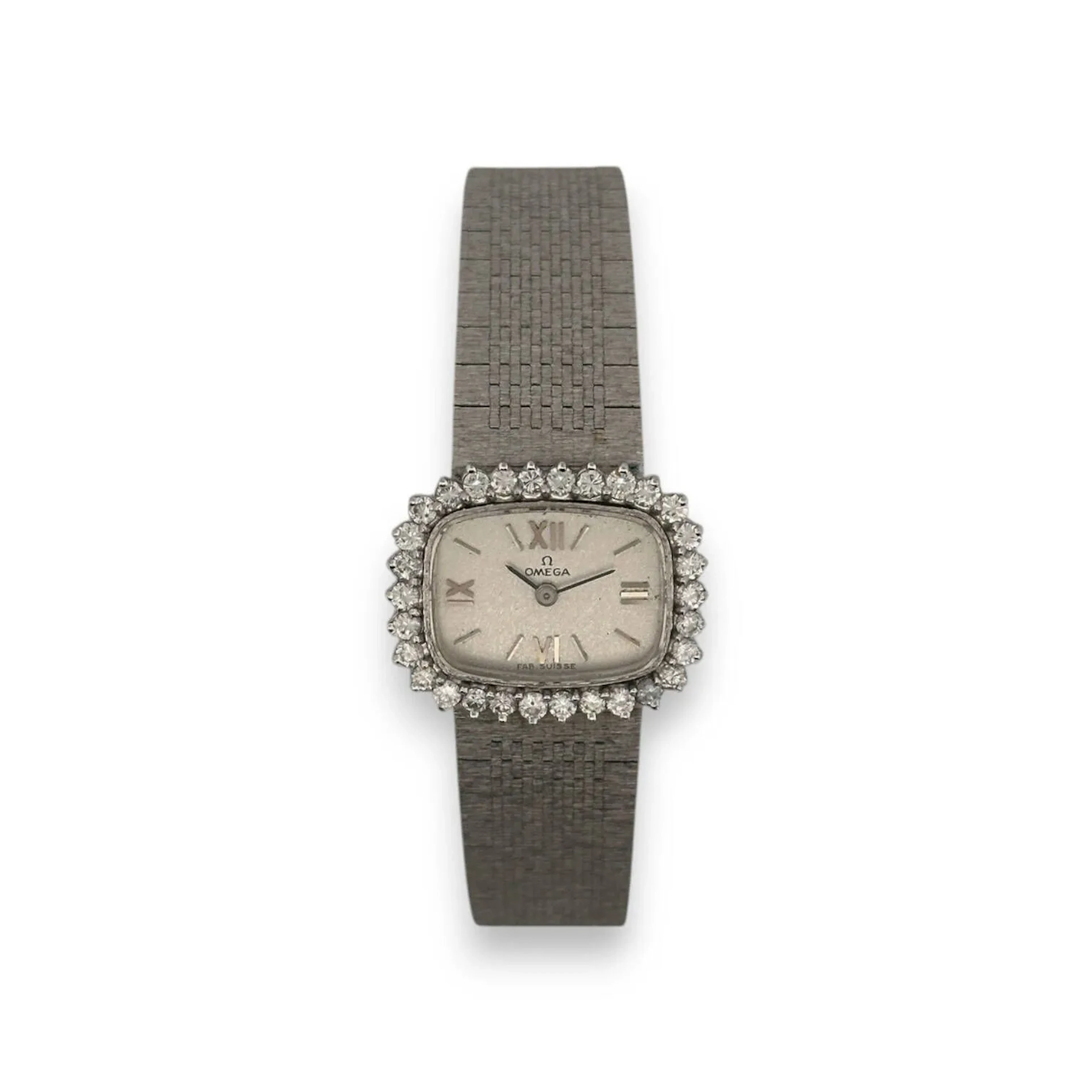 OMEGA Montre bracelet de dame en or gris 18K (750), cadran argenté, lunette ovale sertie de diamants, index chiffres romains et bâtons formant les heures, mouvement mécanique, bracelet intégré en or brossé 18K à boucle cliquet siglée. Cadran signé. Diam. : 21 mm - Poids brut : 42 g.