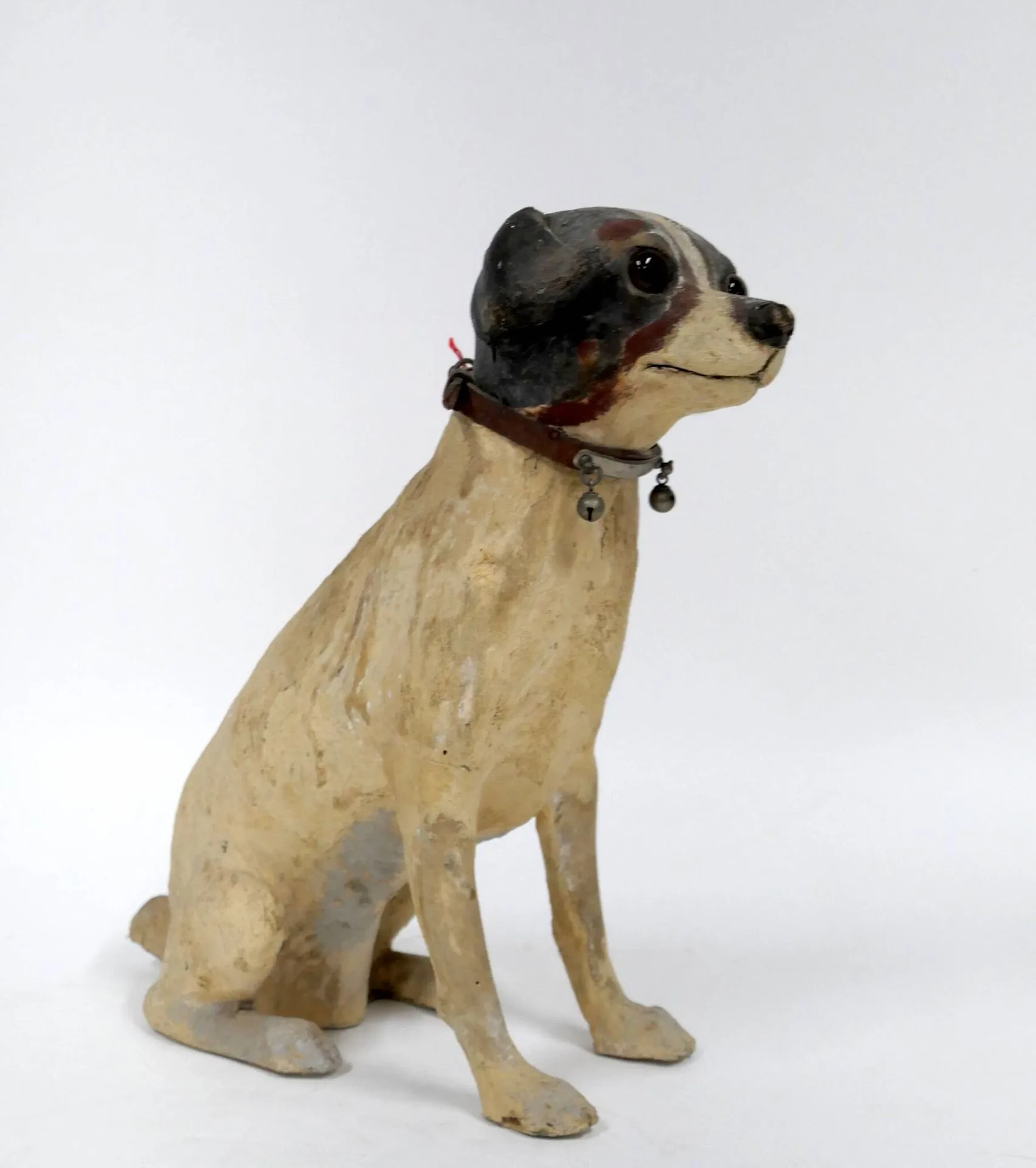 [Jouet ancien] Chien assis au collier à grelots Carton mâché polychrome. Etiquette du vendeur de jeux et jouets "Au Nain Bleu, G.Fauvet, Paris". Tête amovible. Hauteur : 28 cm Etat d'usage