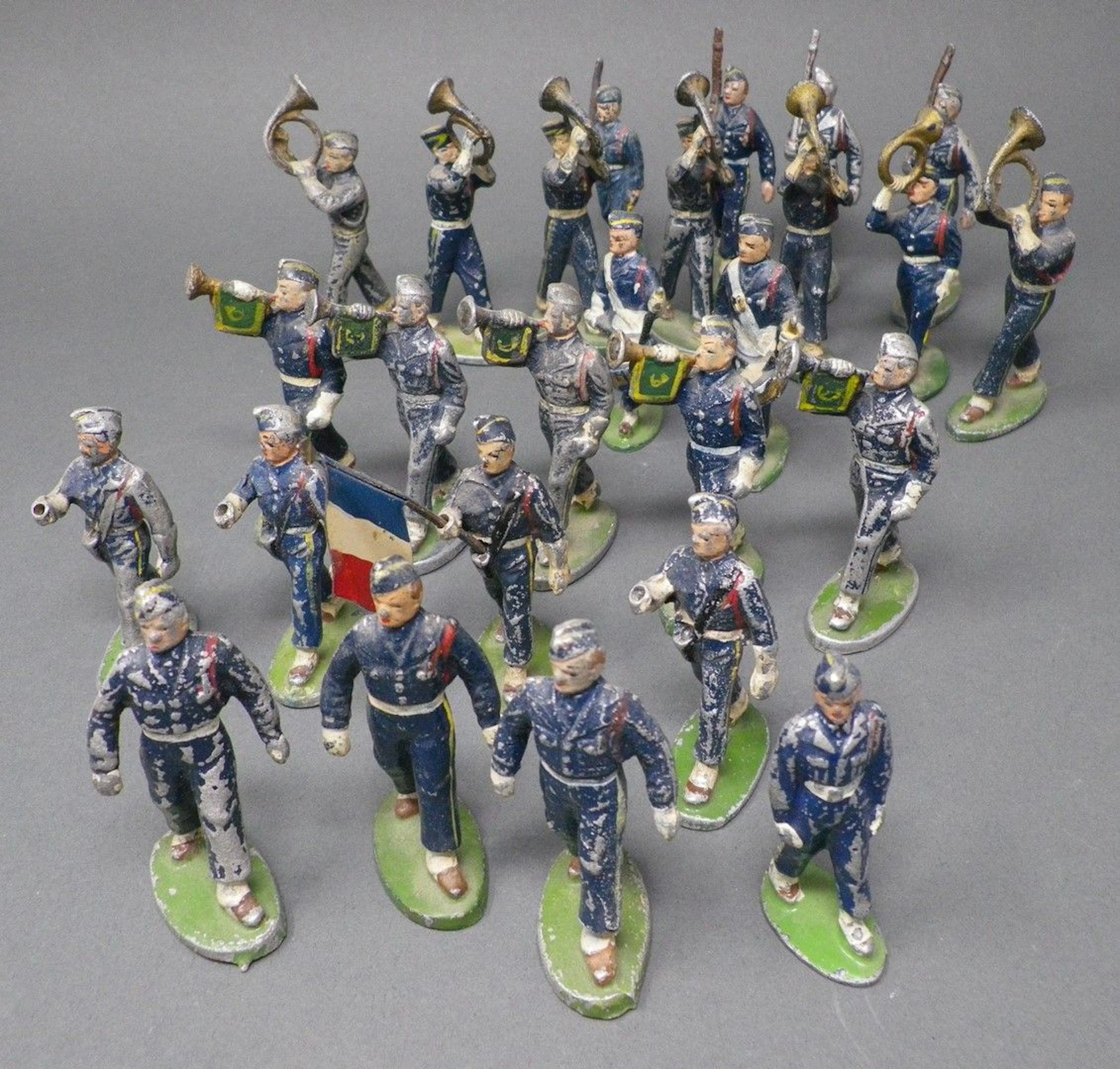QUIRALU - Chasseurs au défilé (1945-1960) Vingt-six figurines dont le porte-drapeau, officier, musiciens, reproduits p. 38 & 39 - Bibliographie : Les jouets Quiralu 1933-1964 - R. Alazet - J. Borsarello - H. Giroud - Ed° J. Granchet Paris. Jouets anciens pouvant présenter des manques de peinture, des chocs ou des manques, y compris pour les conditionnements éventuels. Vendus en l'état et sans réclamations.